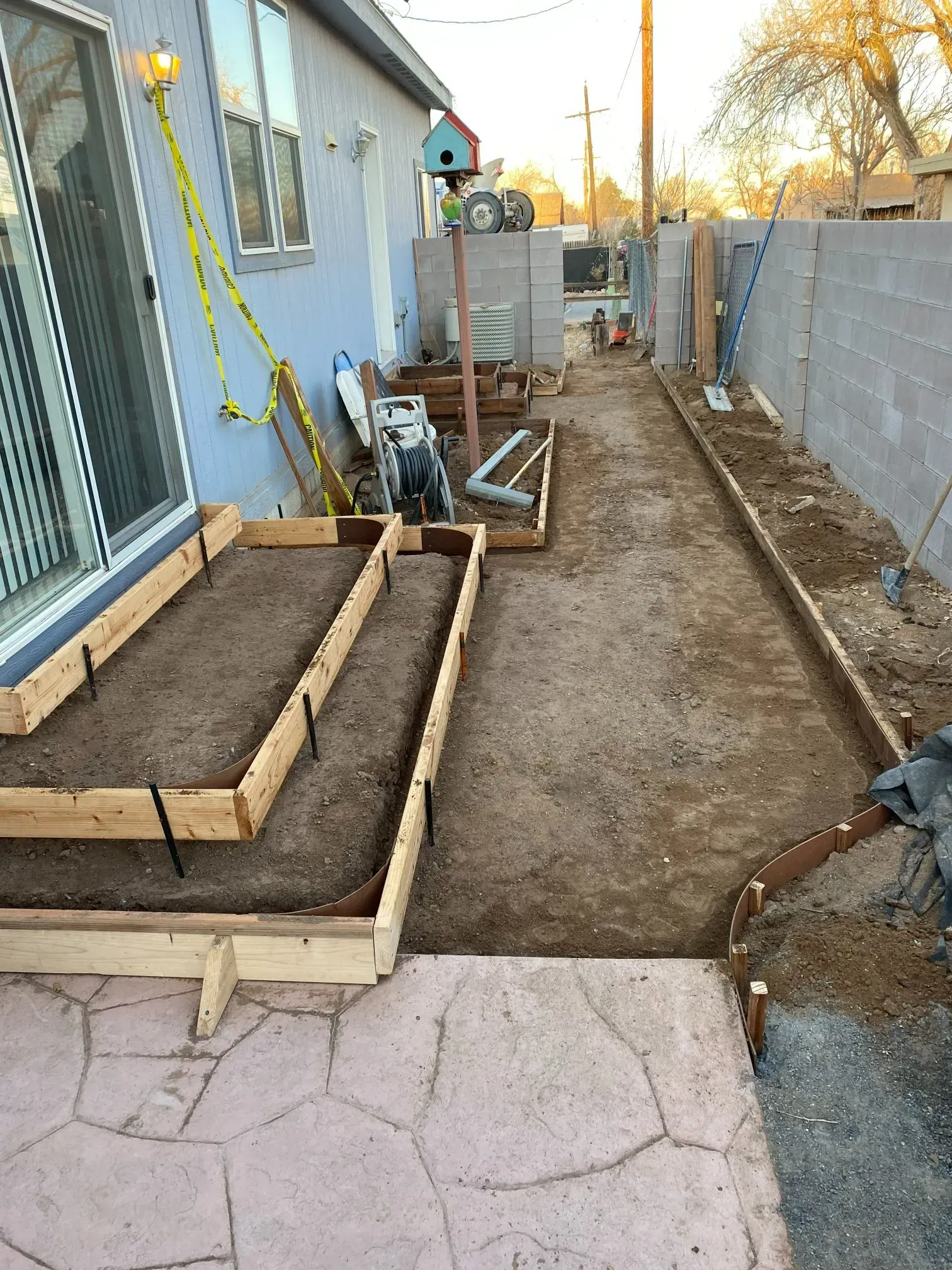 A concrete walkway is being built in the backyard of a house.