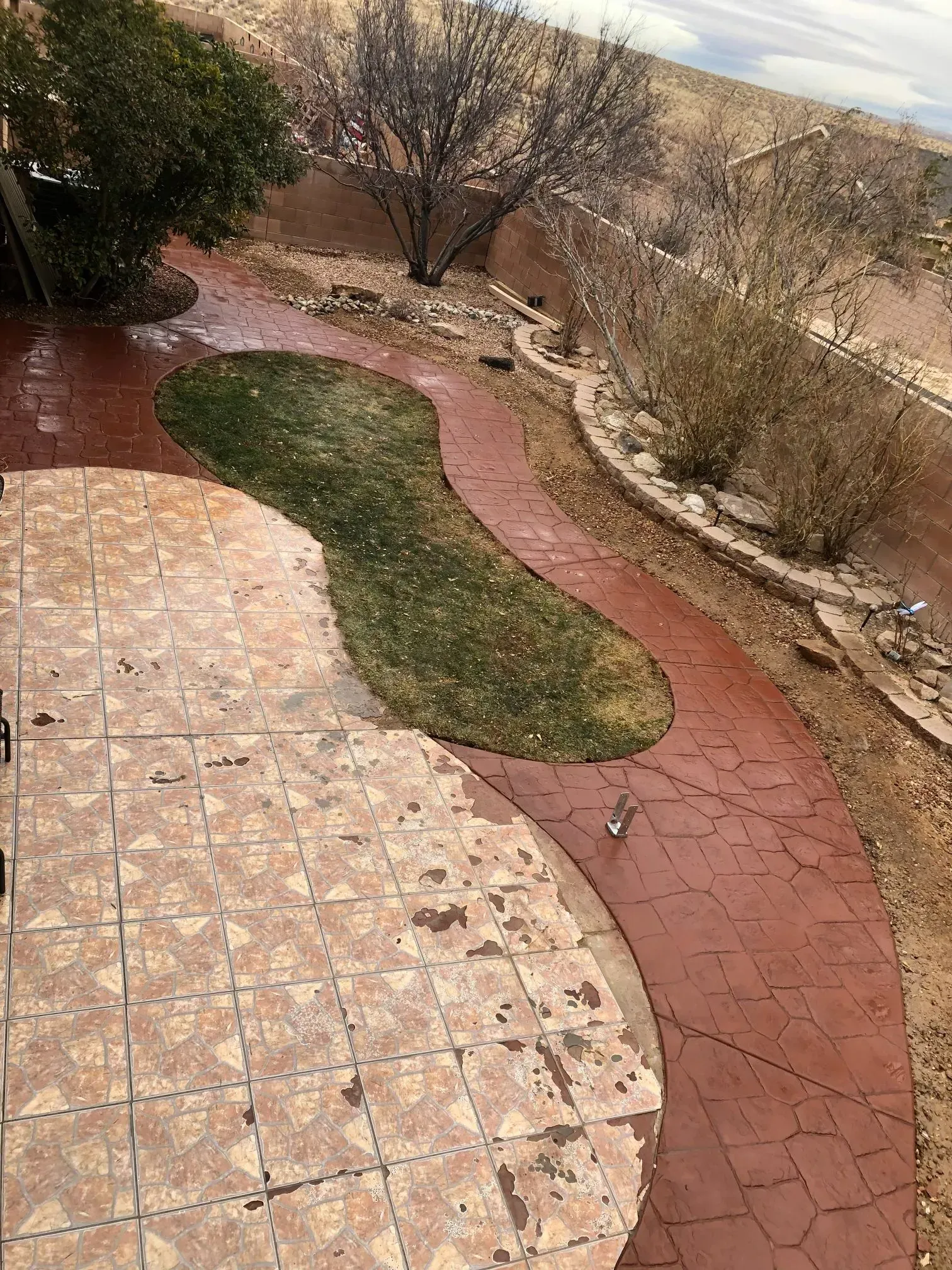 A brick walkway leading to a grassy area next to a patio.