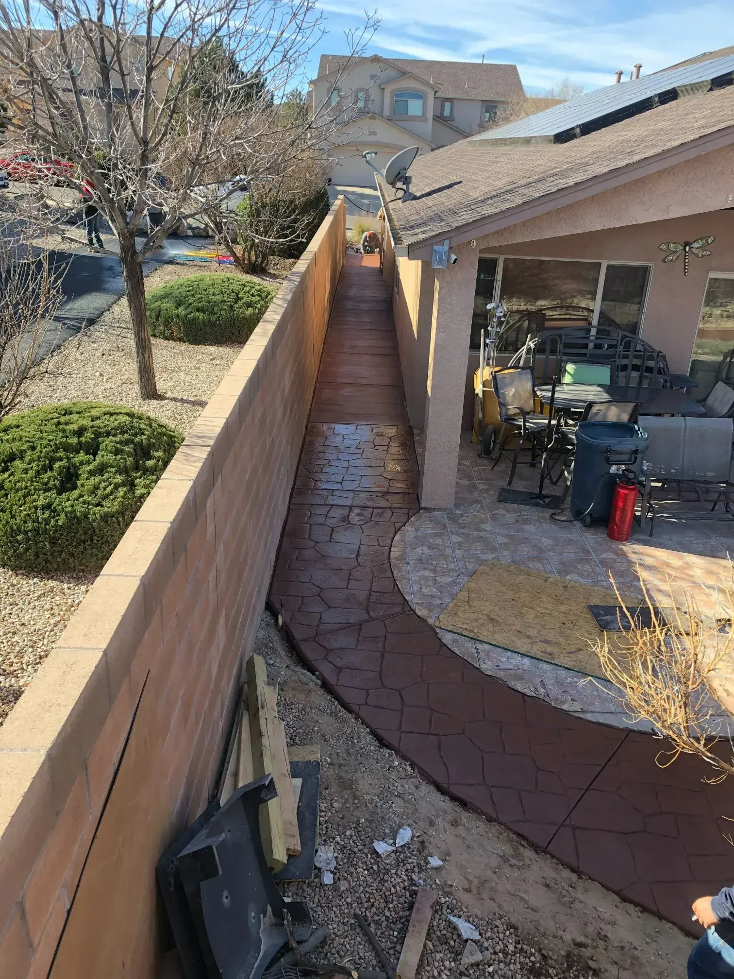 A concrete walkway leading to a patio next to a house.