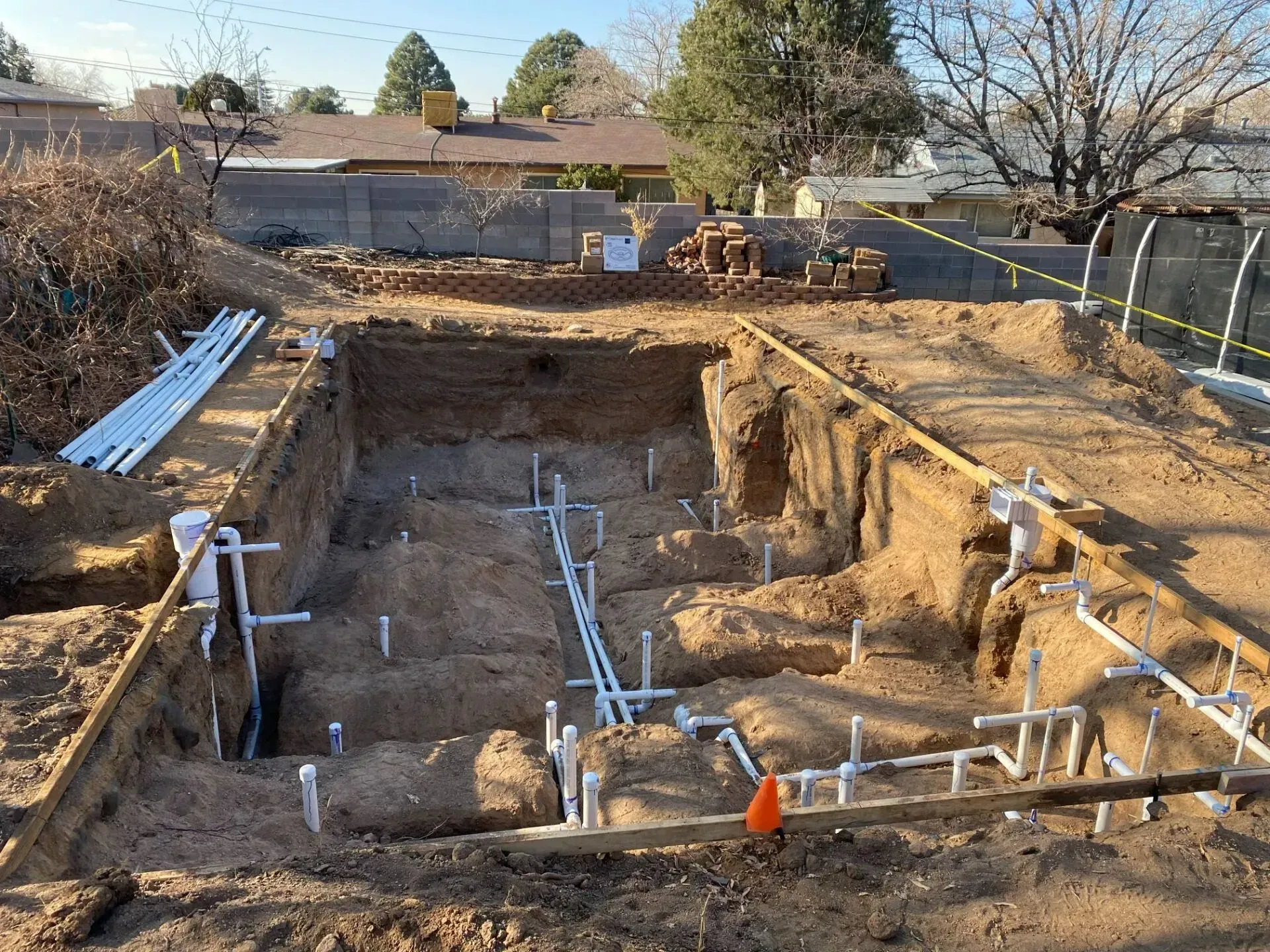 A swimming pool is being built in the dirt in front of a house.