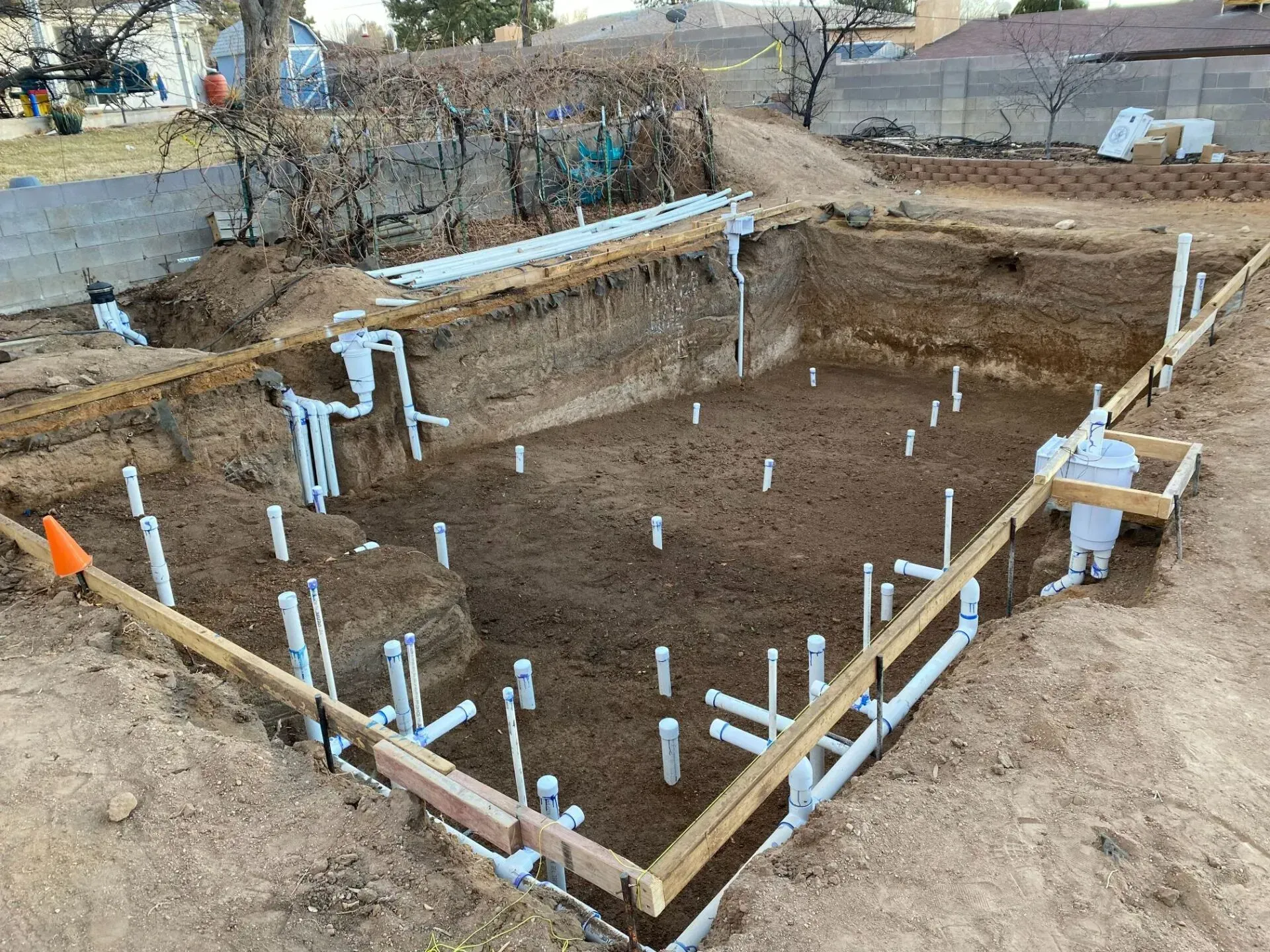 A swimming pool is being built in the backyard of a house.