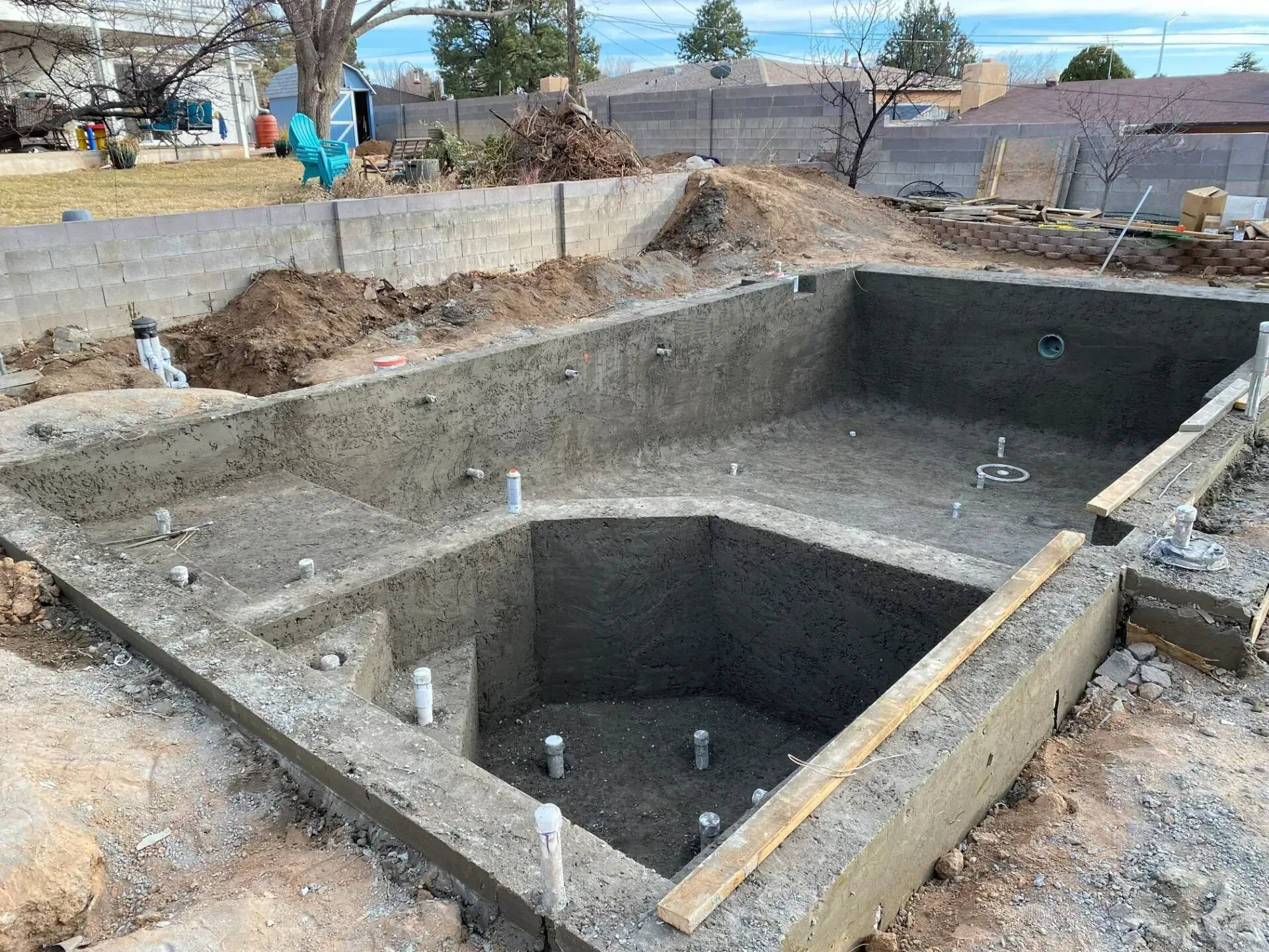 A large concrete pool is being built in a backyard.