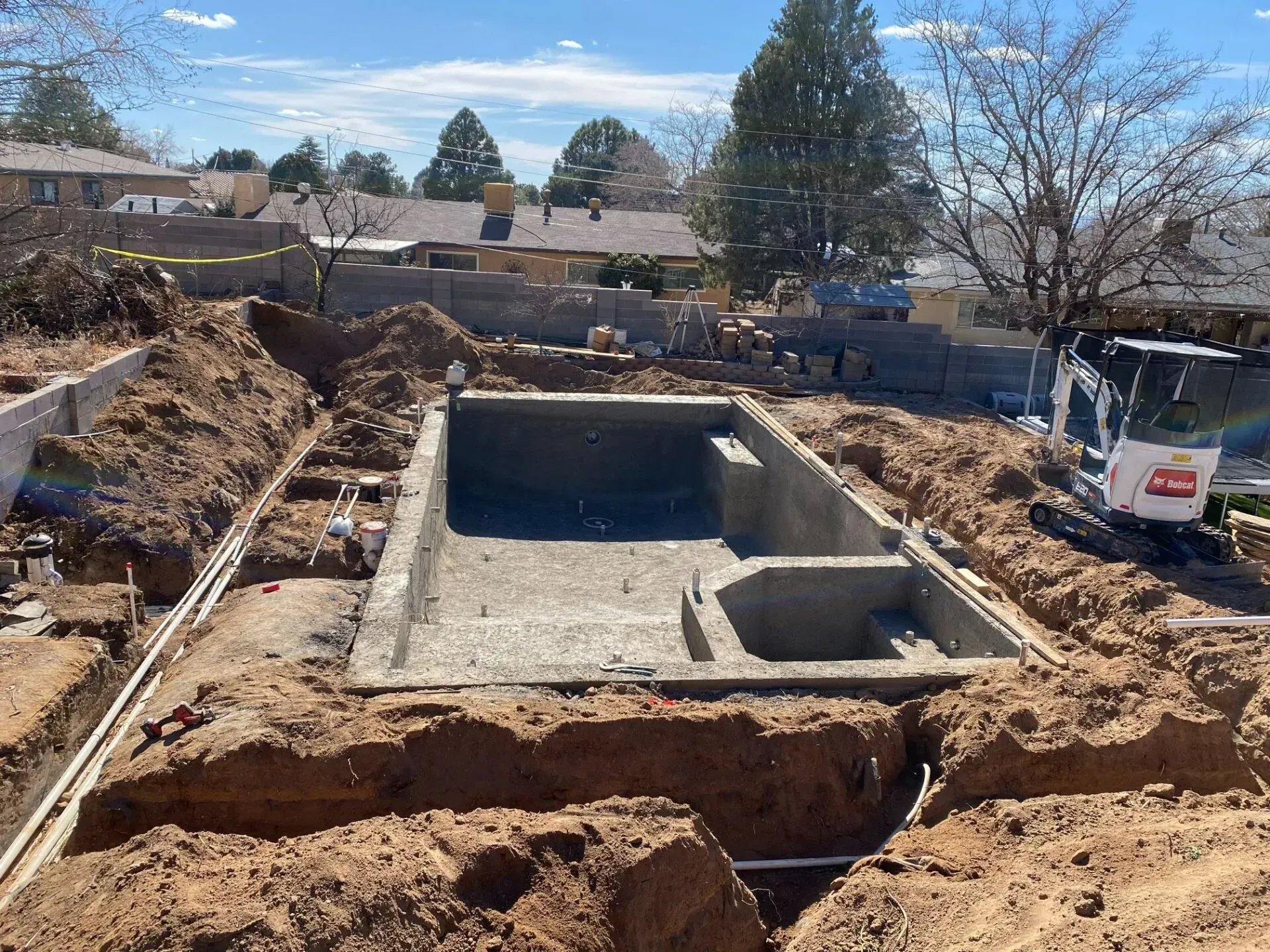 A large swimming pool is being built in a dirt field.