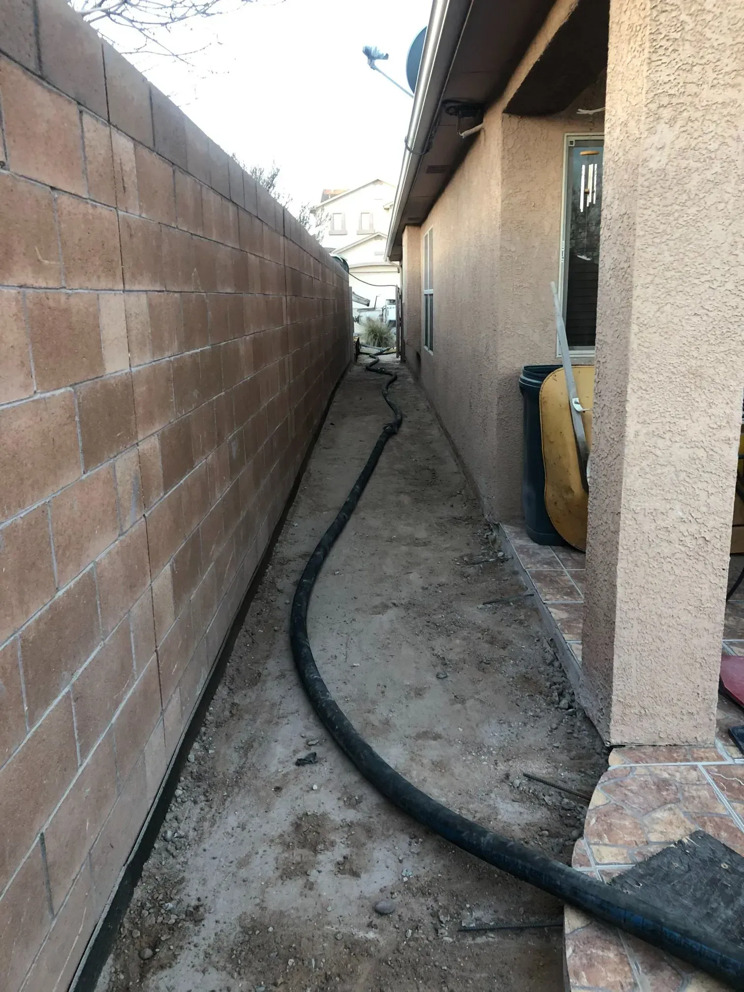 A hose is connected to a brick wall next to a house.