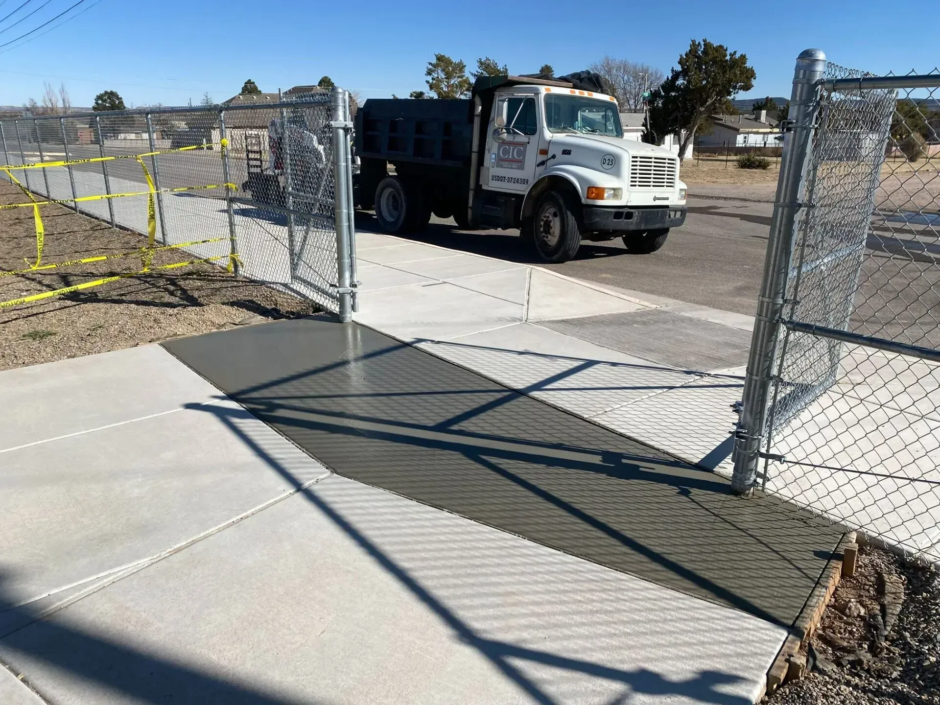 A white truck is parked next to a chain link fence.