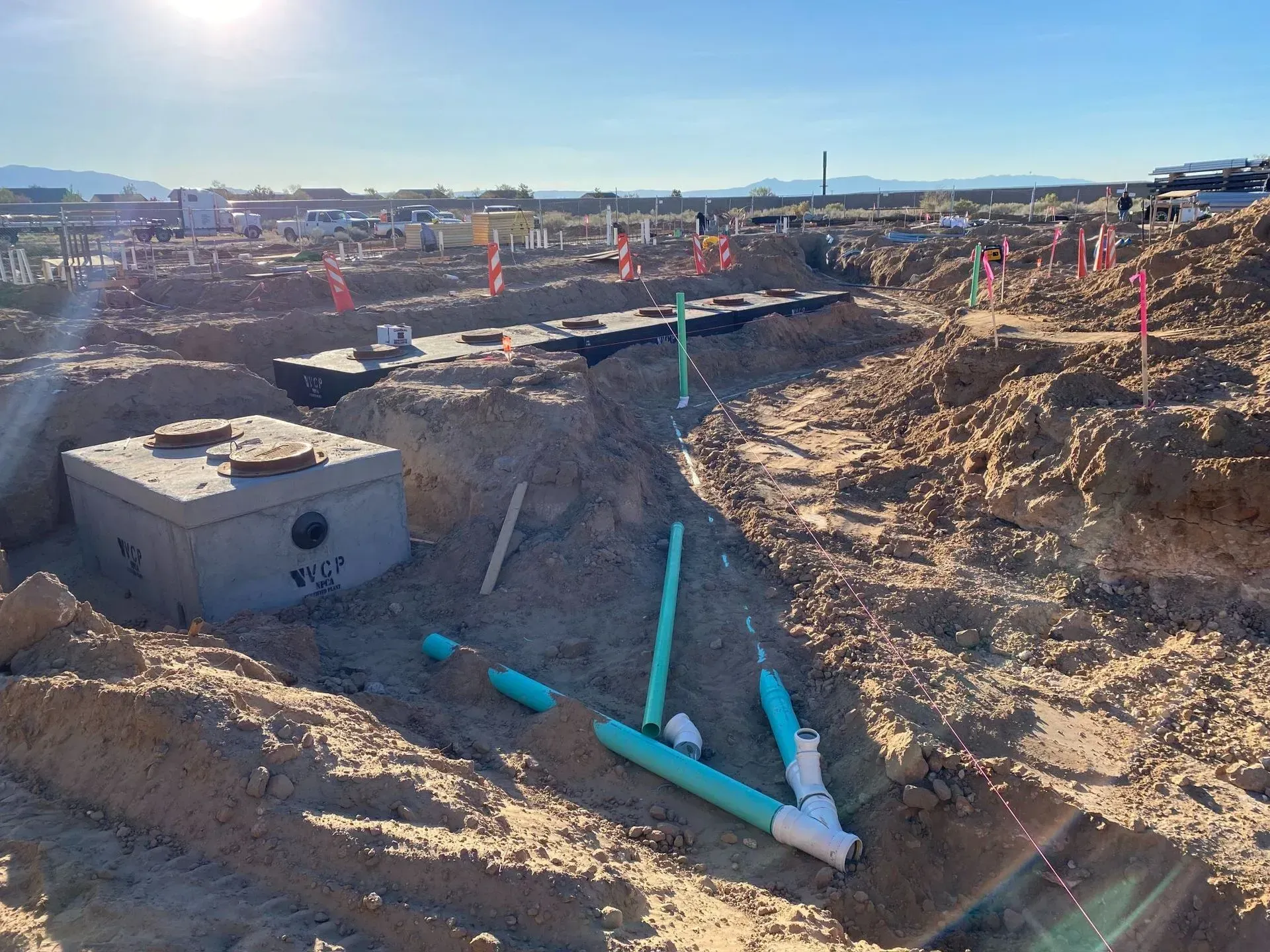 A construction site with a septic tank and pipes in the dirt.