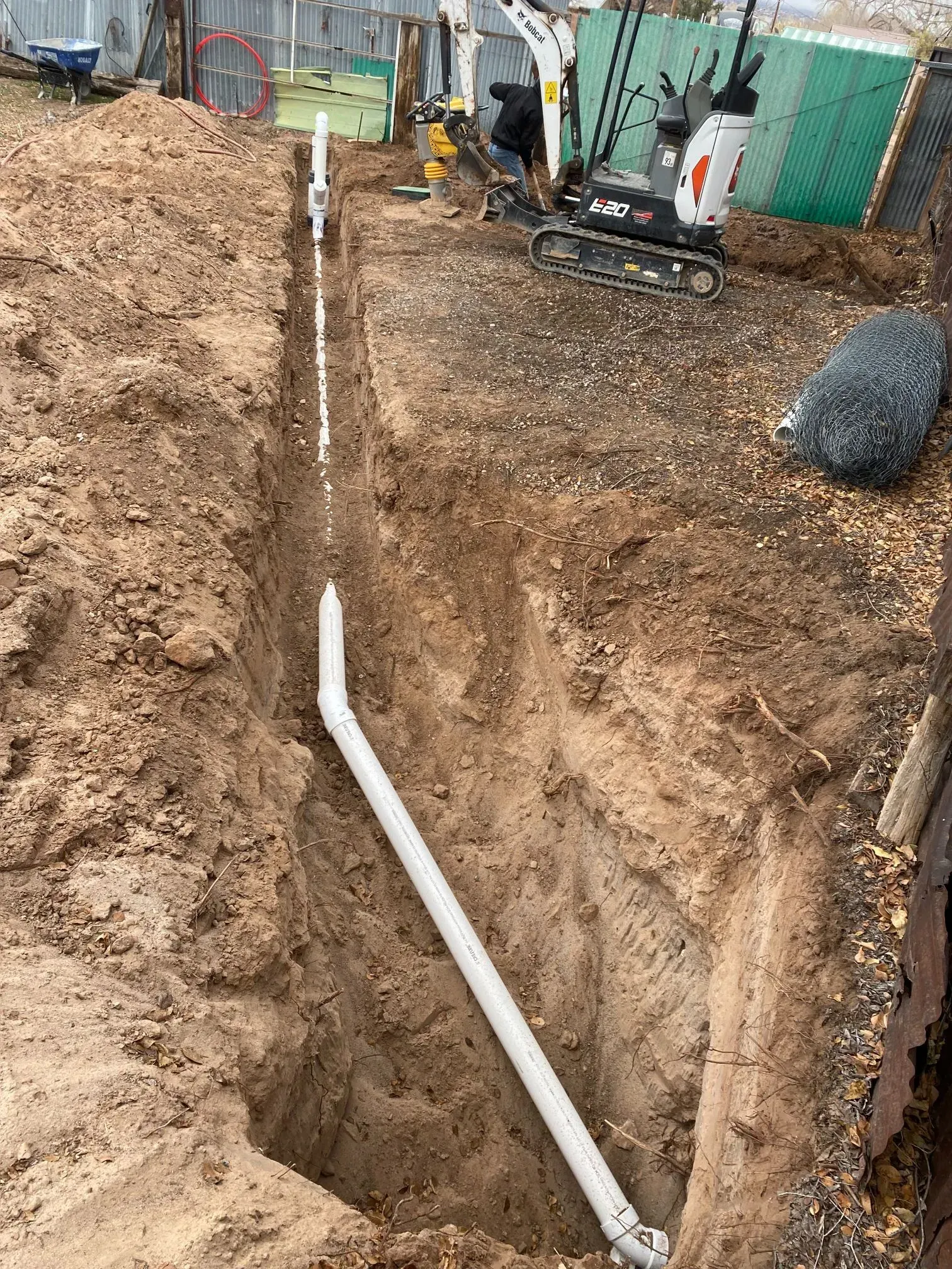 A white pipe is being installed in a hole in the ground.