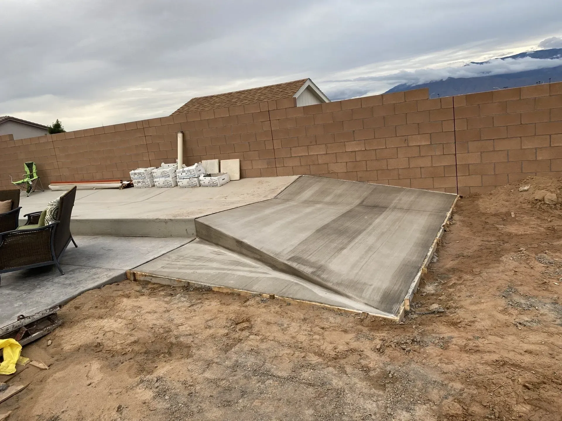 A concrete ramp is being built in the backyard of a house.