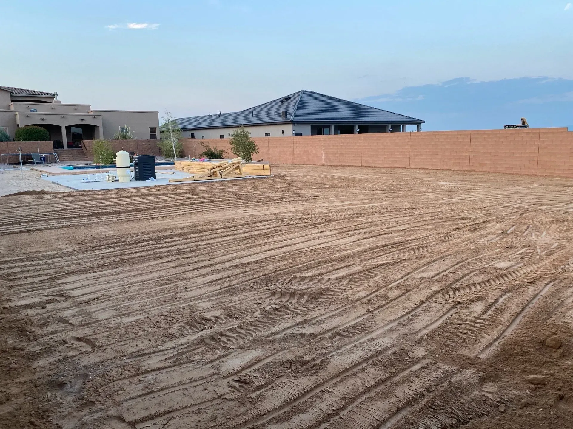 A large dirt field with a house in the background.
