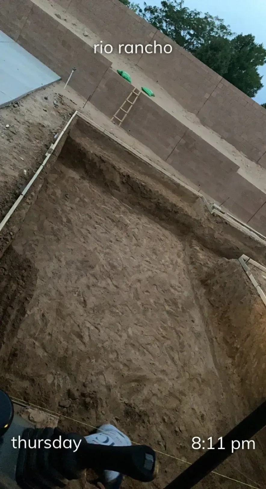 A person is holding a camera in front of a large pile of dirt.