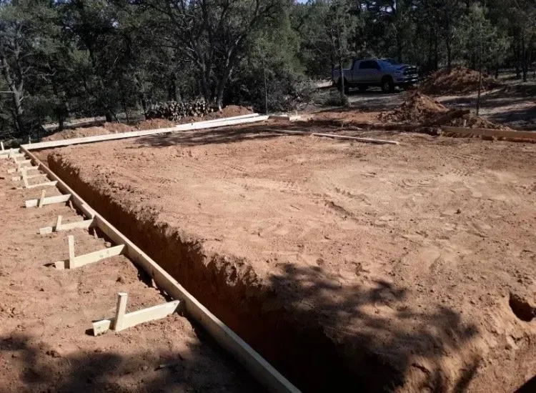 A wooden fence is being built in a dirt field.