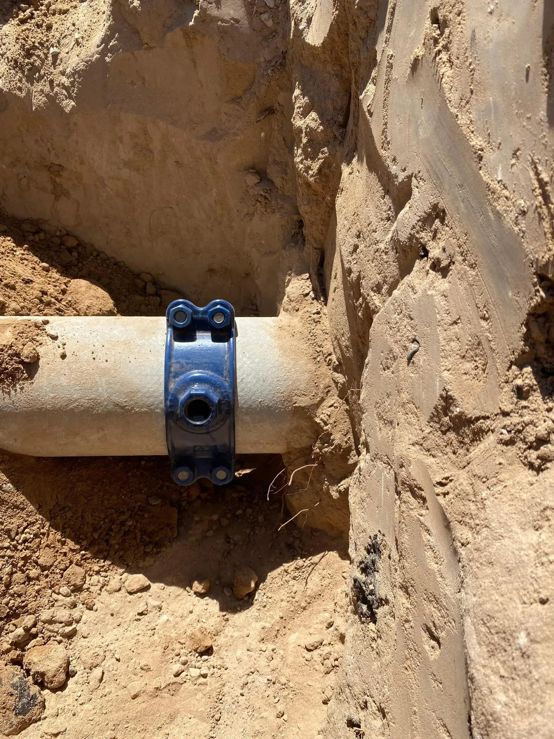 A pipe is sitting in the dirt next to a rock.