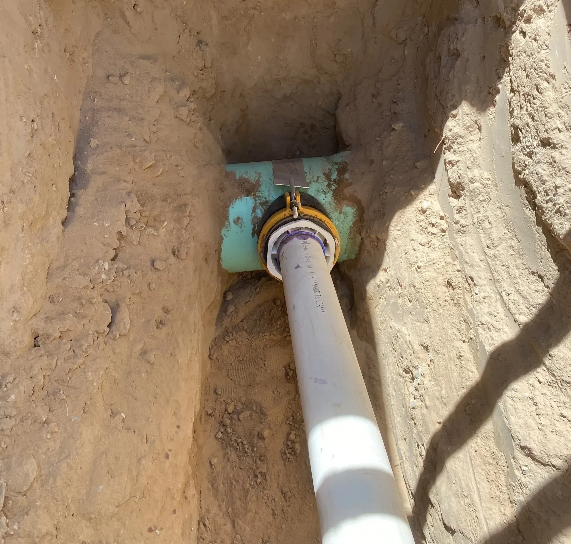 A white pipe is laying in a hole in the dirt