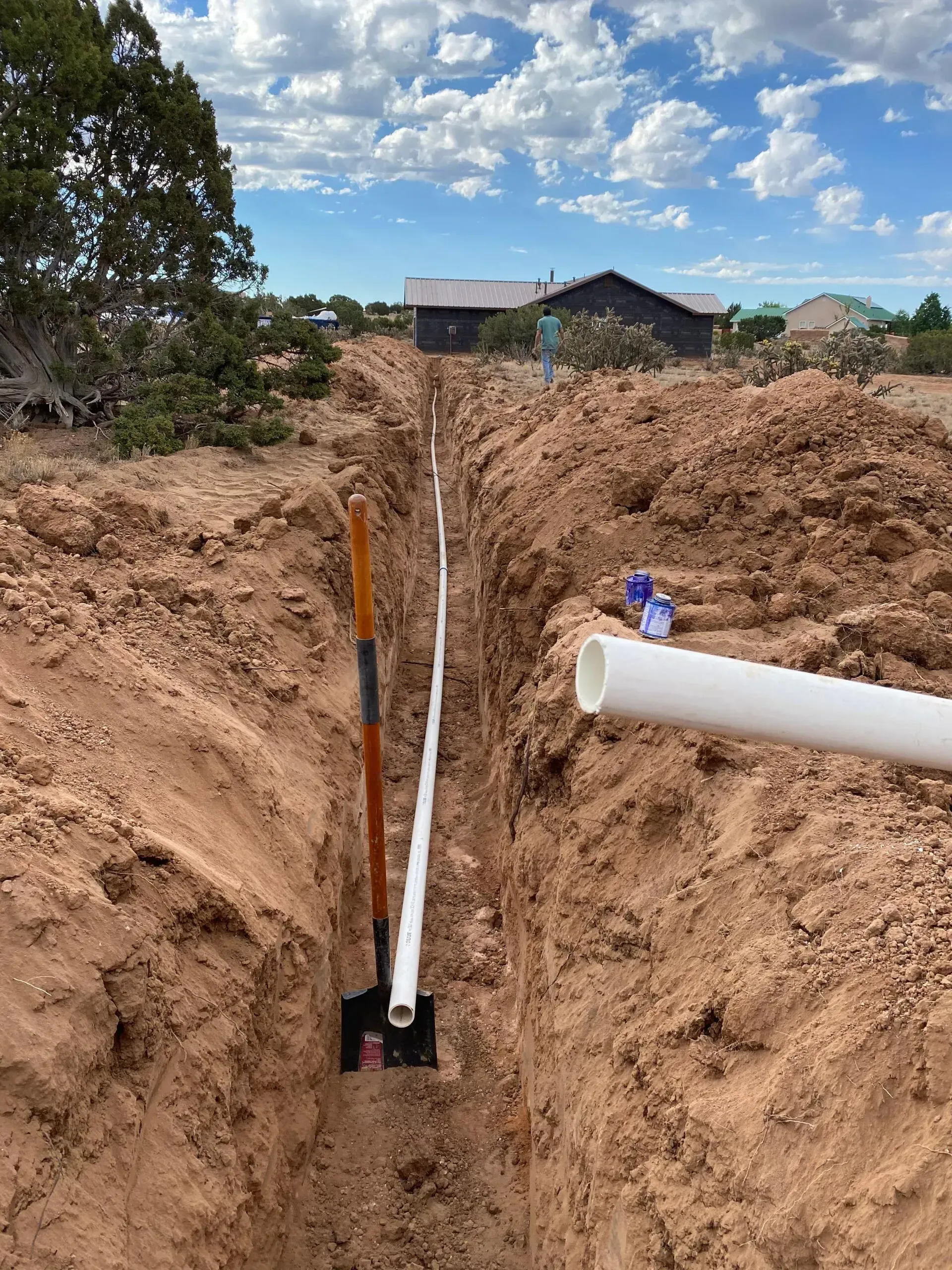 A shovel is sitting in the dirt next to a pipe.