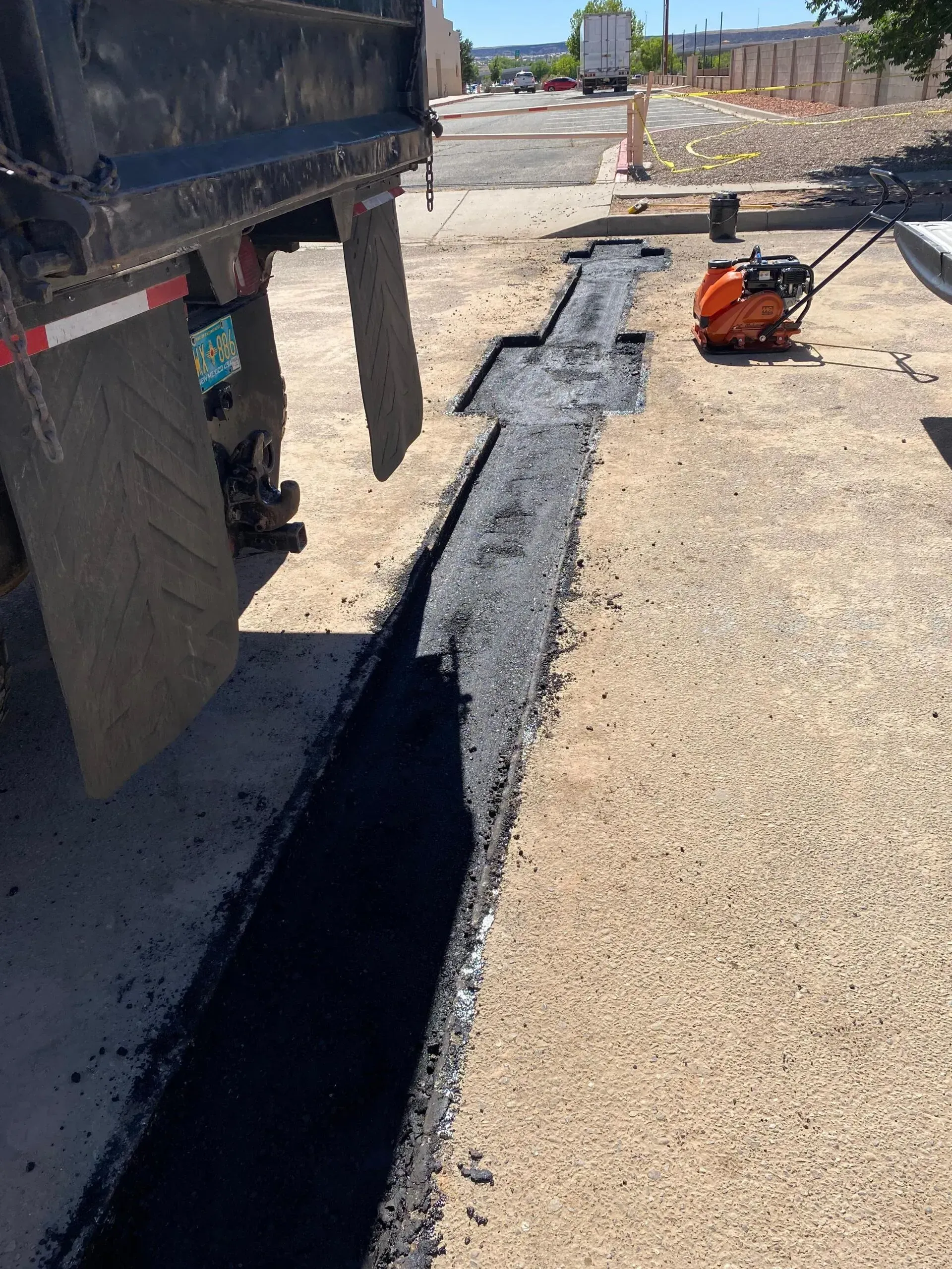 A truck is laying asphalt on the side of the road.