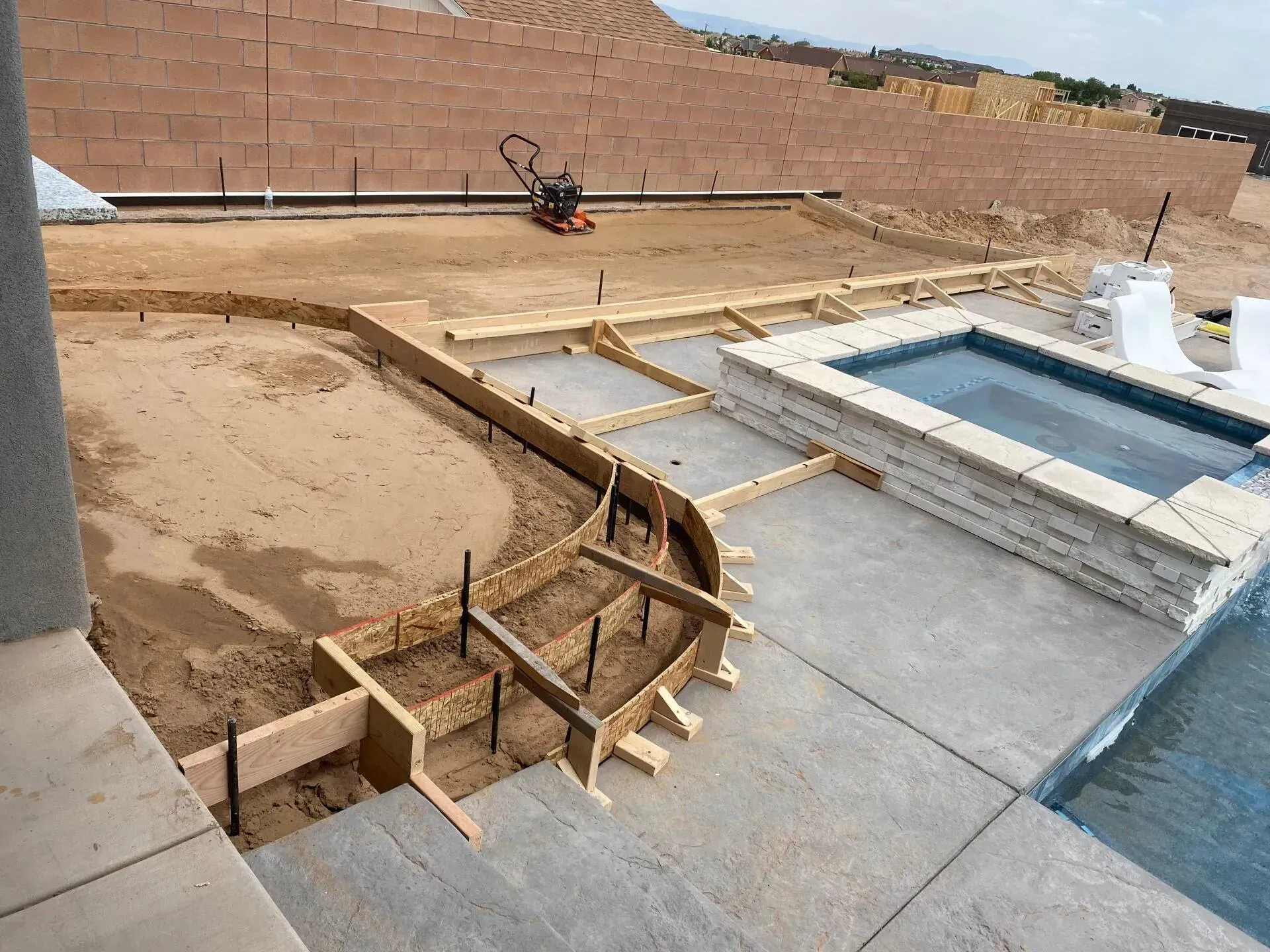 A concrete patio is being built next to a swimming pool.