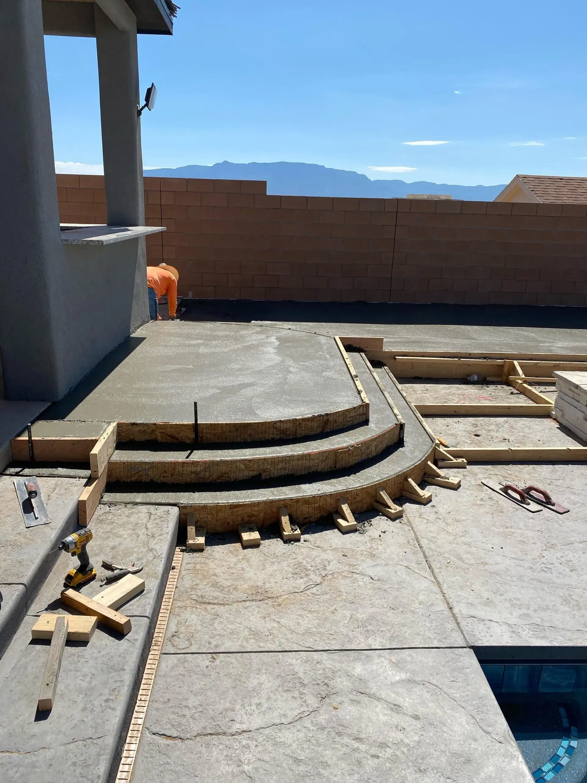 A concrete patio is being built next to a pool