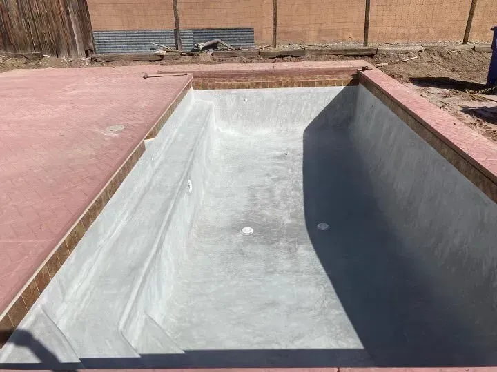 An empty swimming pool is being built in a backyard.