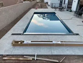 A large swimming pool is being built in the backyard of a house.