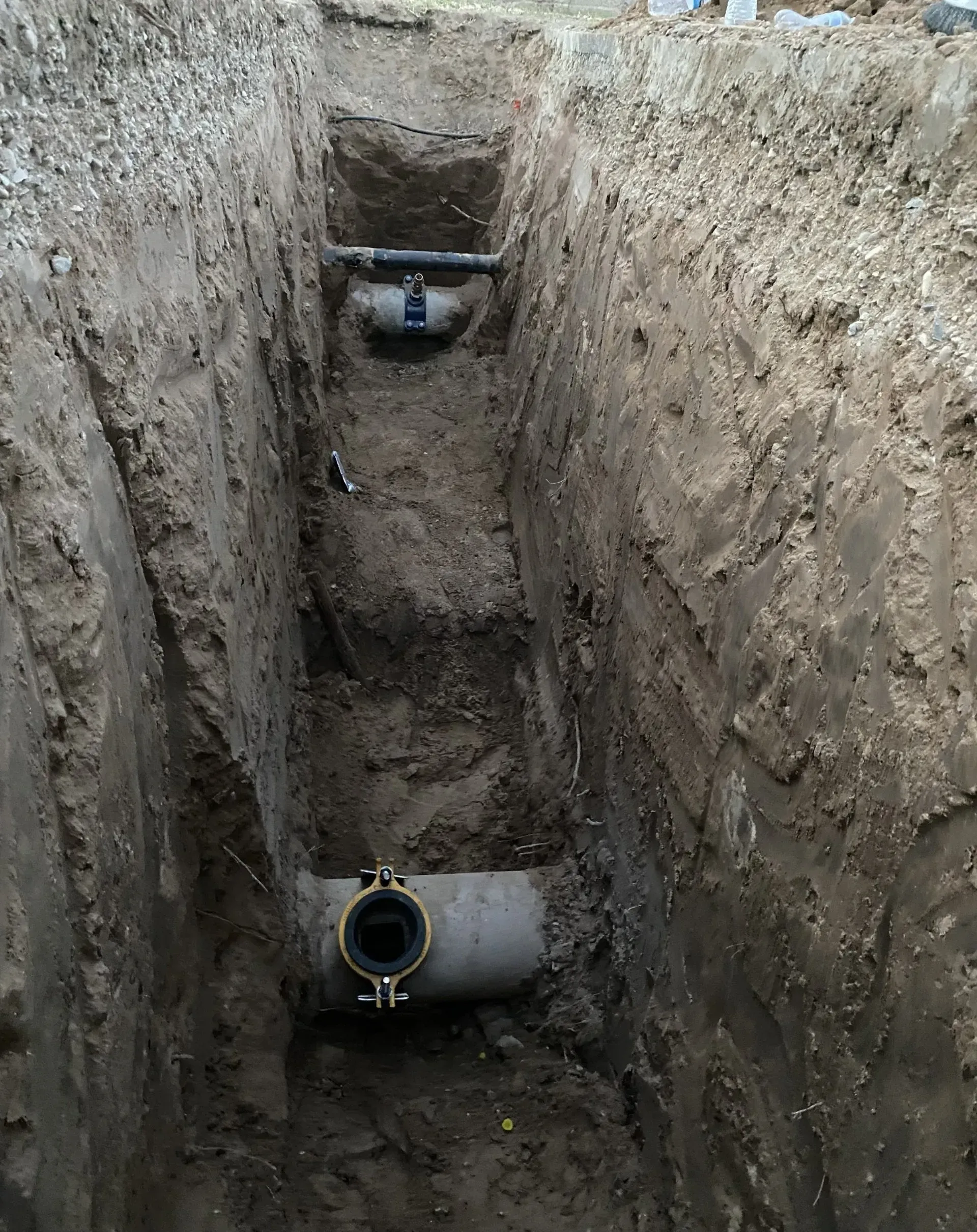 A drain pipe is being installed in a trench.