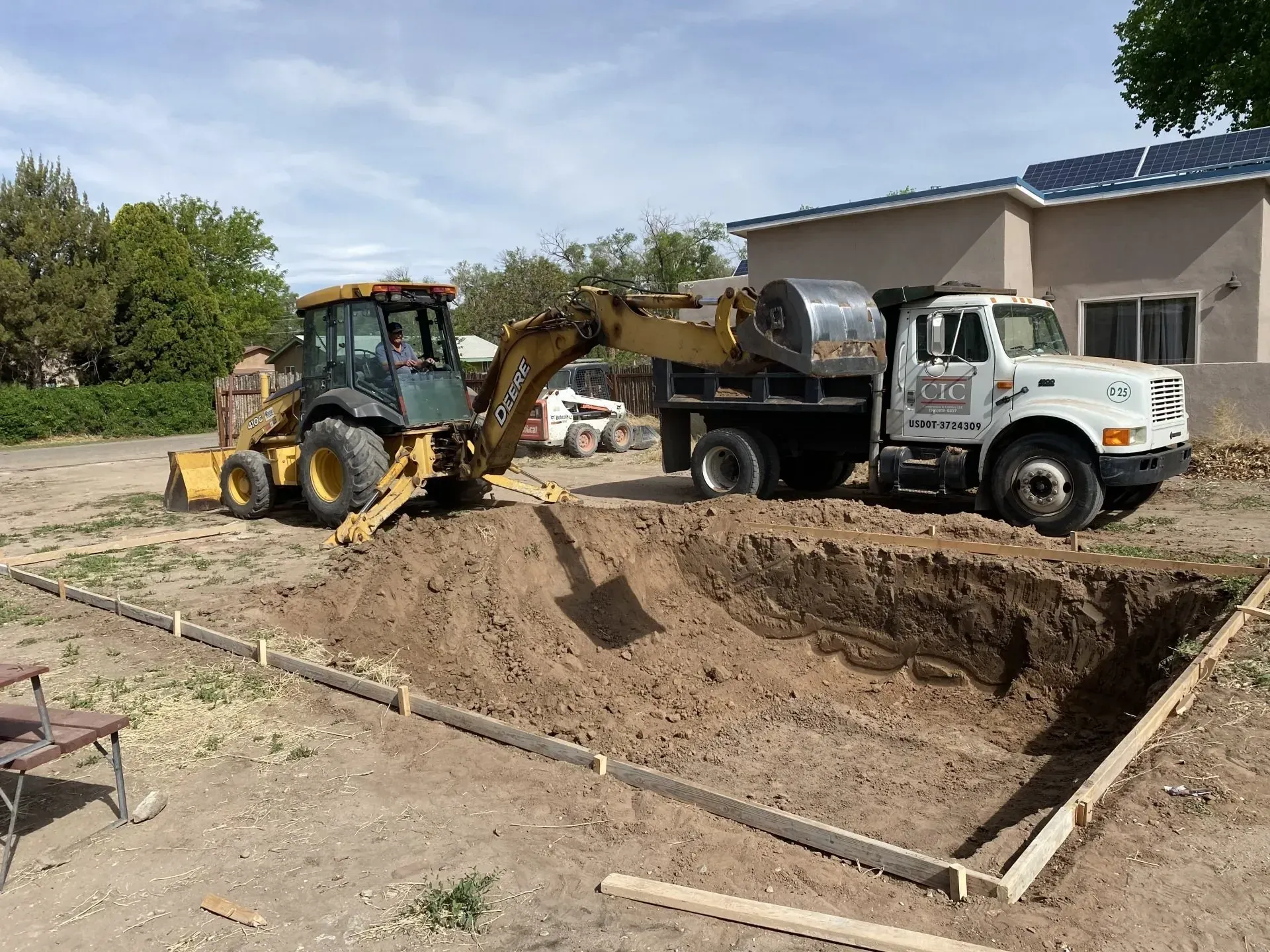 A tractor is loading dirt into a dump truck.