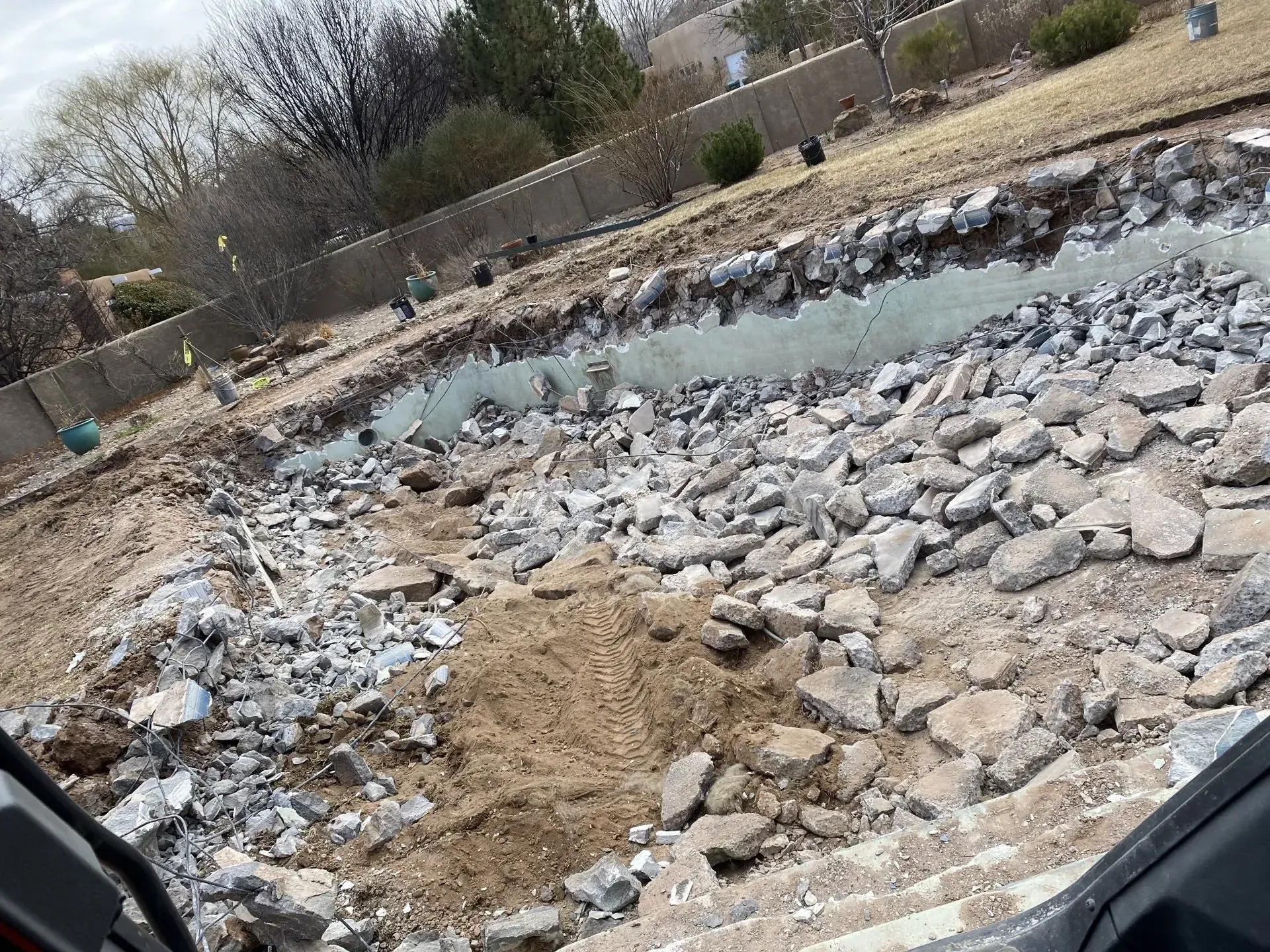 A large pile of rocks and dirt is being demolished in a backyard.