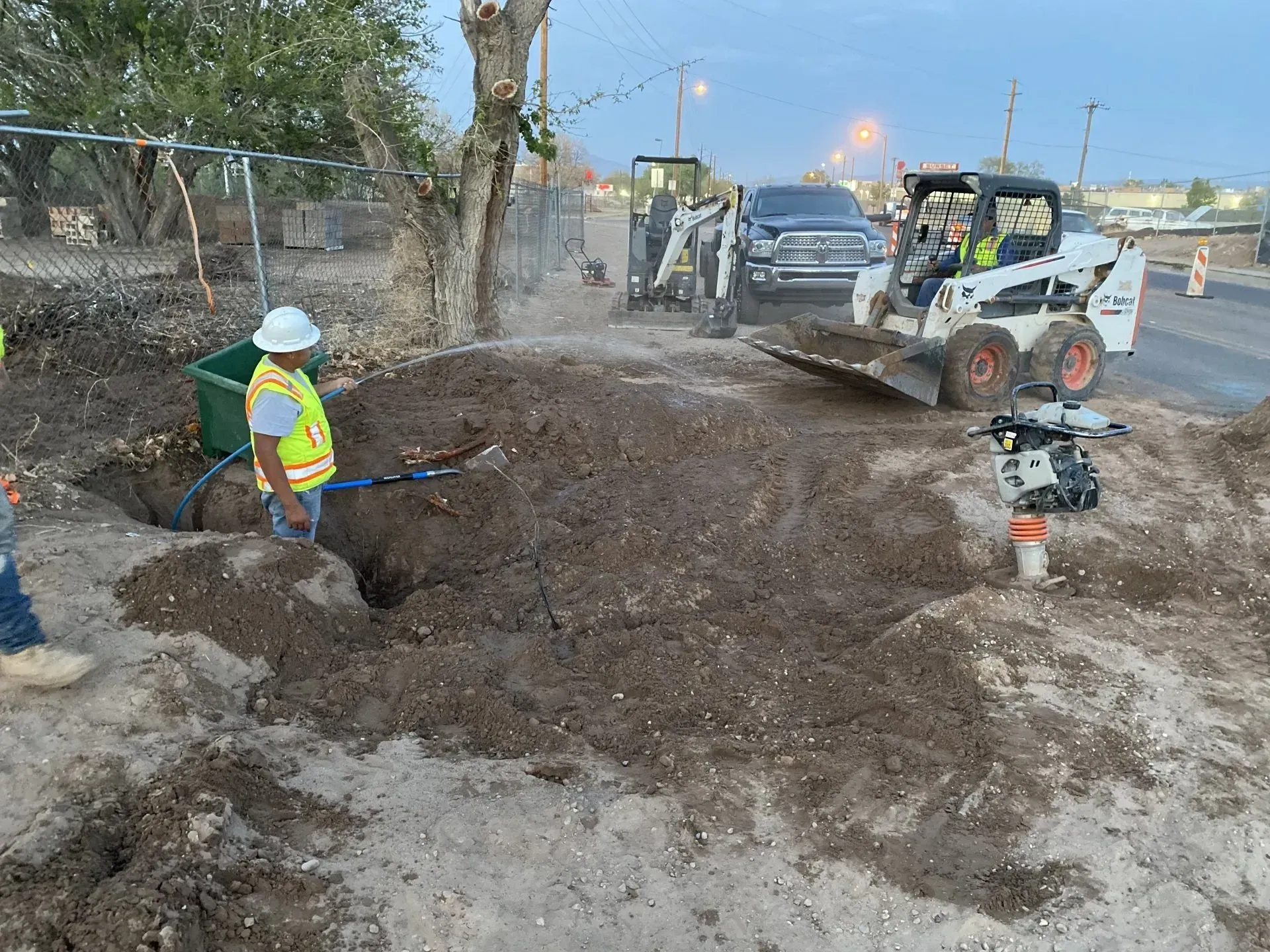 A man is digging a hole in the dirt next to a bulldozer.