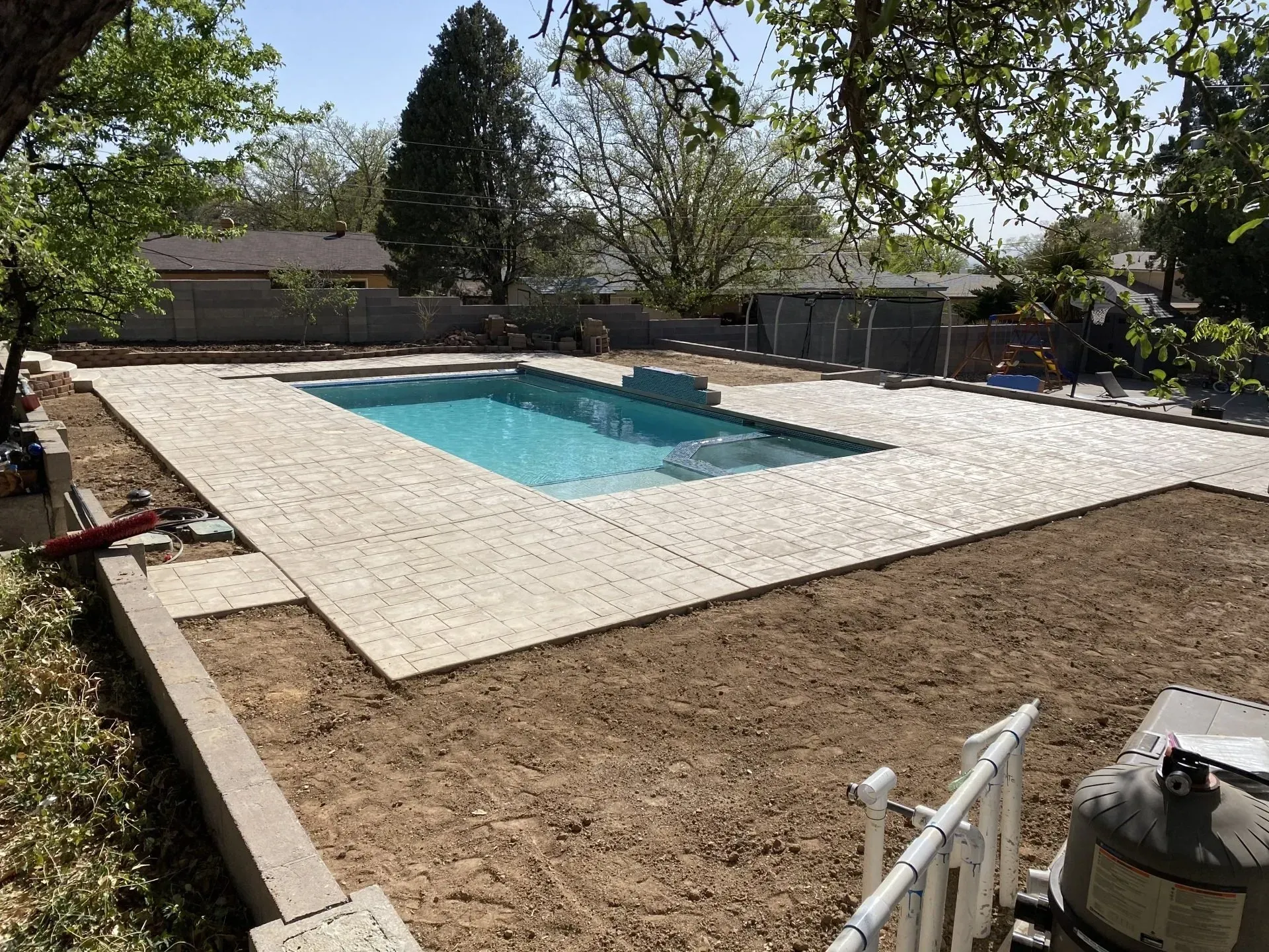 A large swimming pool is being built in the backyard of a house.