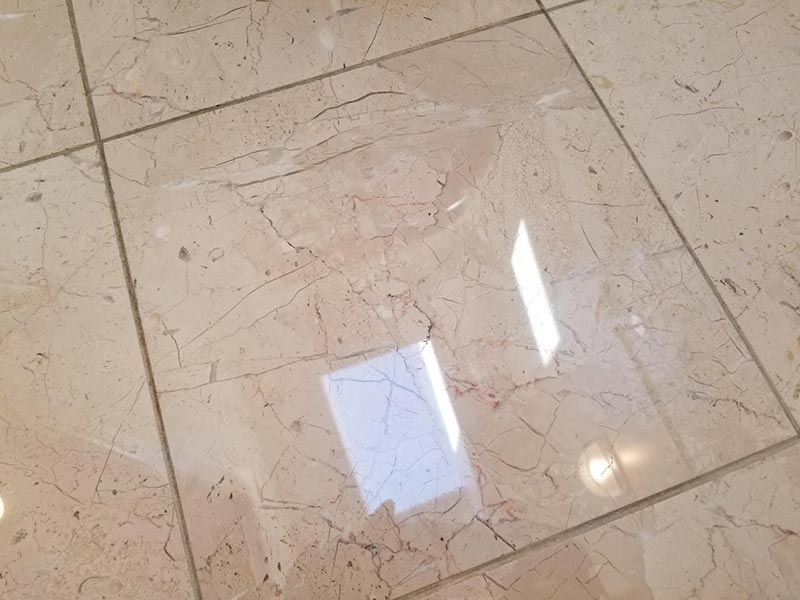 A close up of a tiled floor with a reflection of a window.