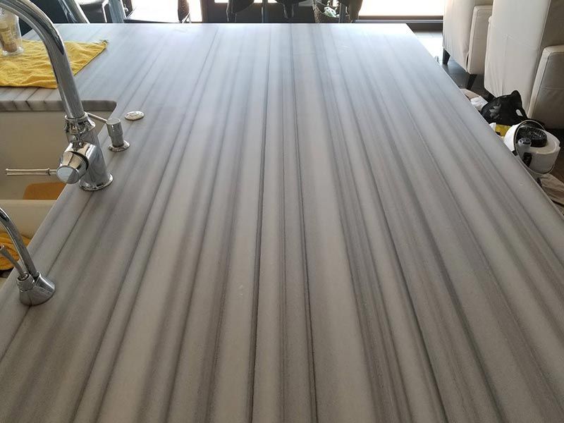 A picture frame is sitting on a marble counter next to wooden utensils.