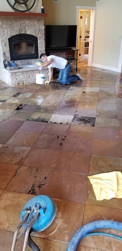 A man is cleaning a tile floor in a living room.