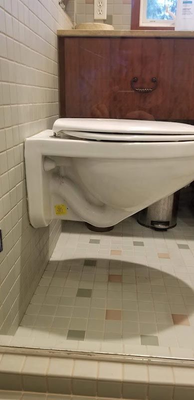 A toilet is mounted to the wall in a bathroom.