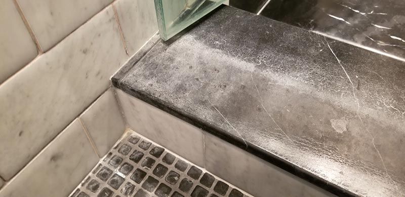 A bathroom with a marble counter top and a tiled floor.
