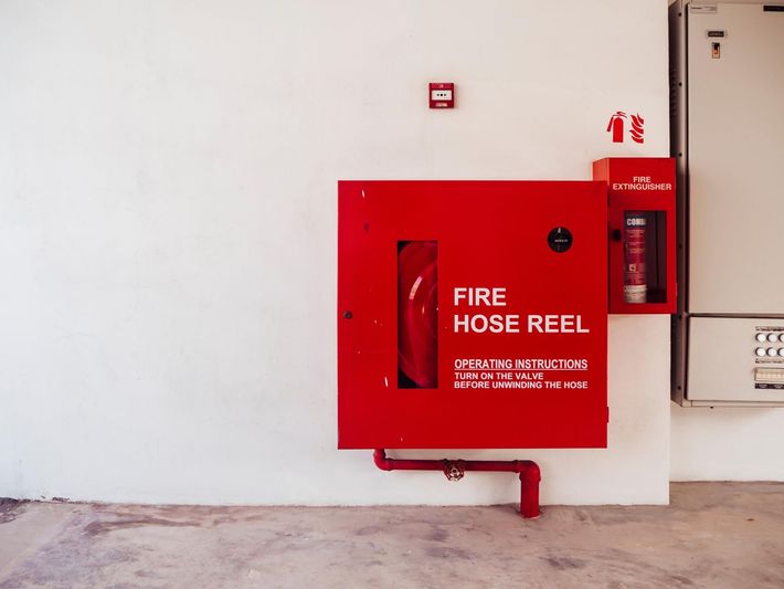 A red fire hose reel is attached to a white wall.