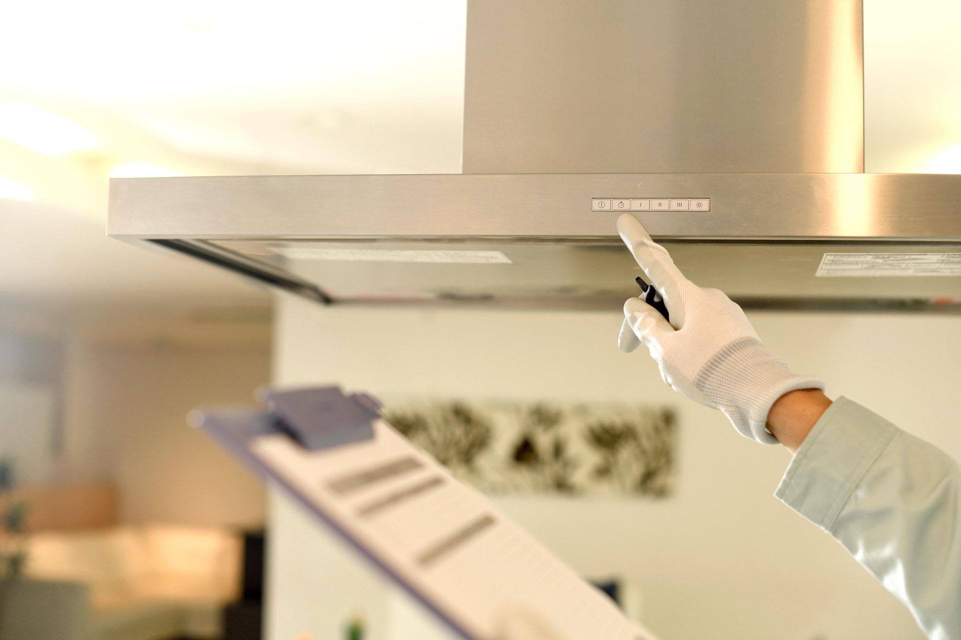 A person is pointing at a ceiling fan while holding a clipboard.