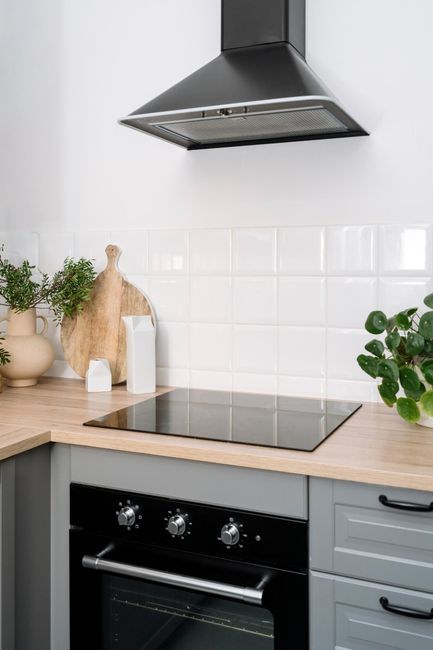 A kitchen with a stove top oven and a hood above it.