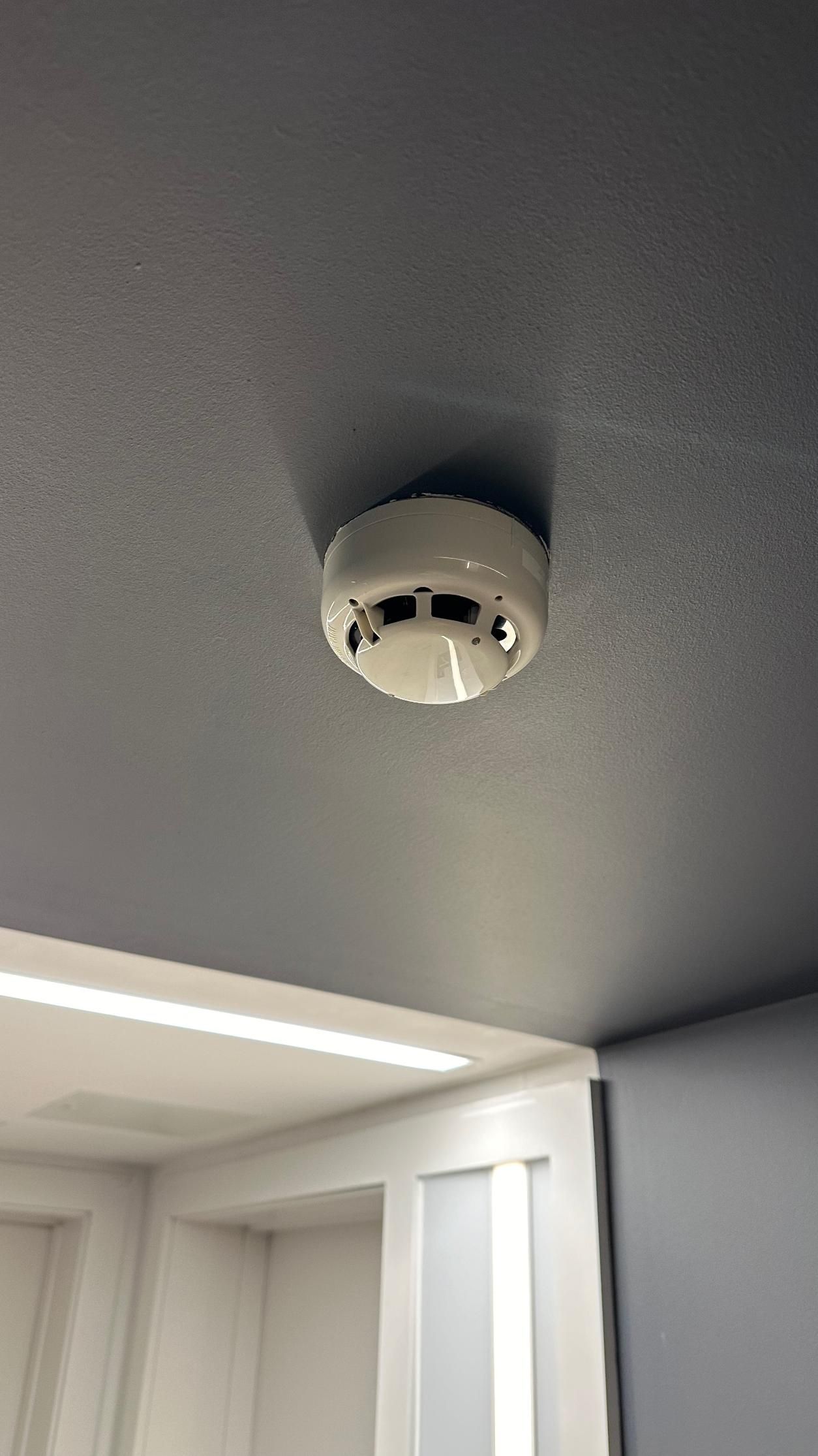 A smoke detector is hanging from the ceiling of a room.