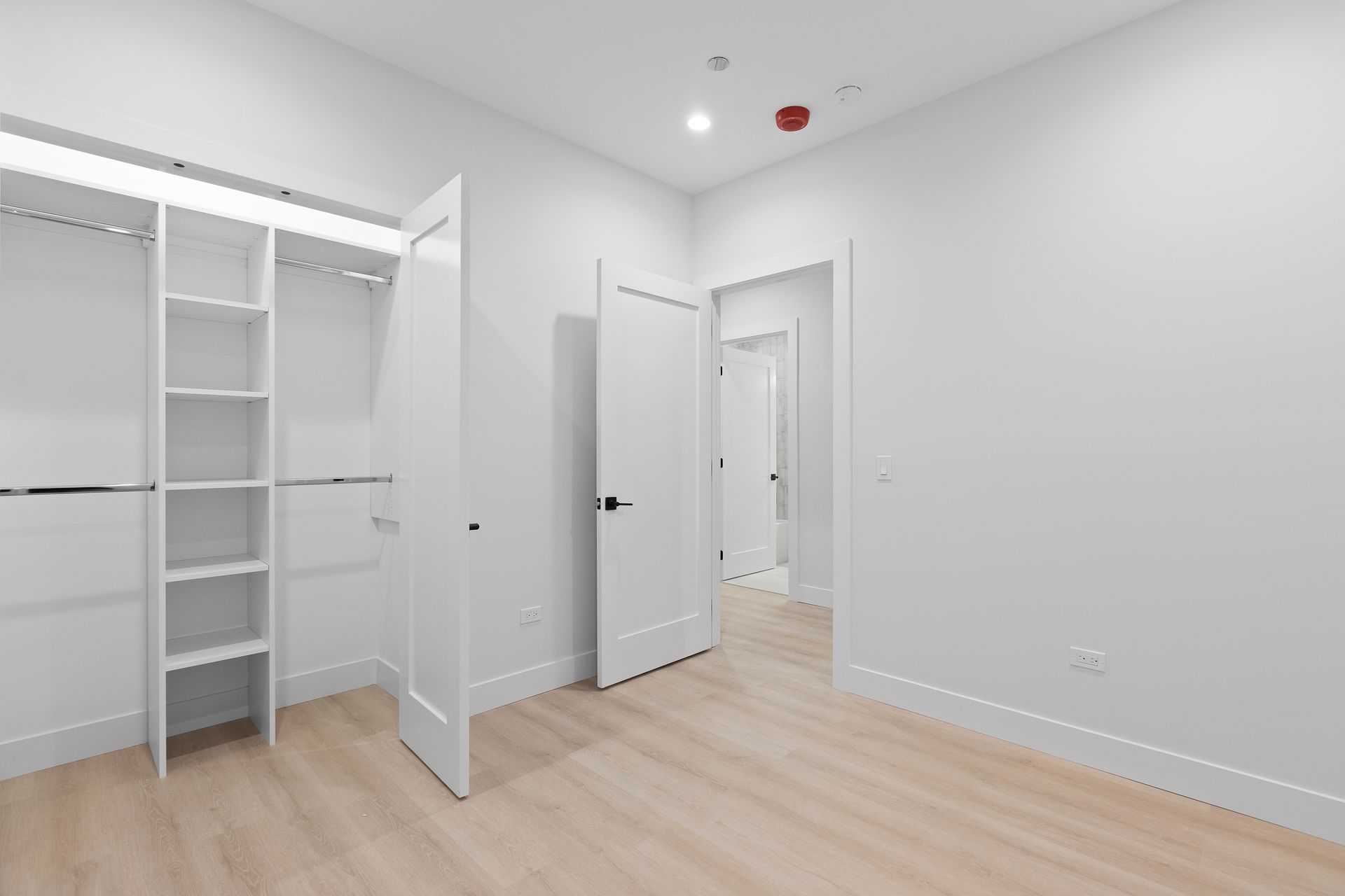 An empty bedroom with a walk in closet and hardwood floors.