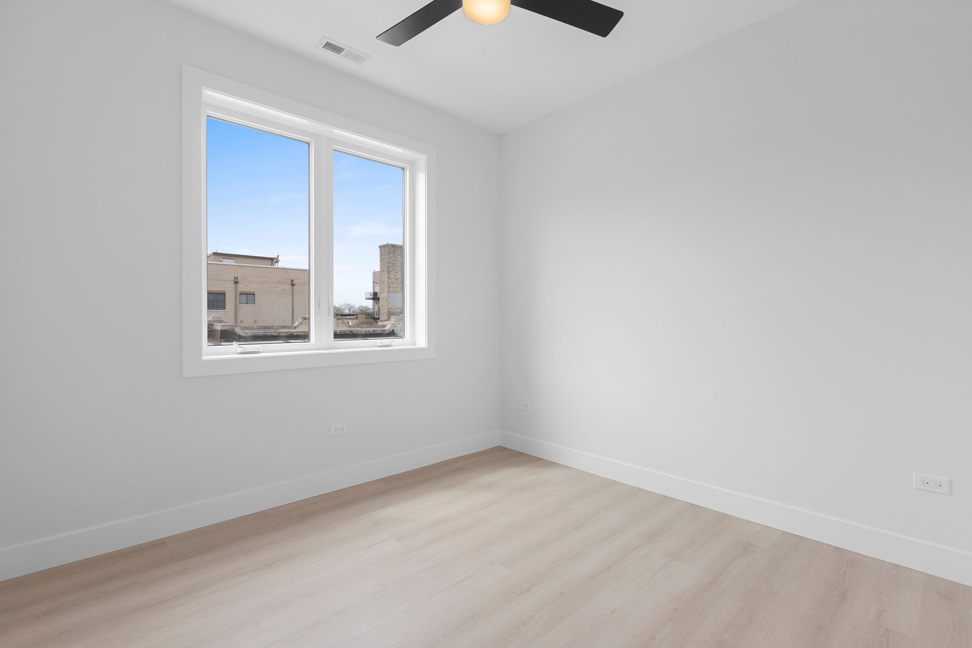 An empty room with a ceiling fan and a window.