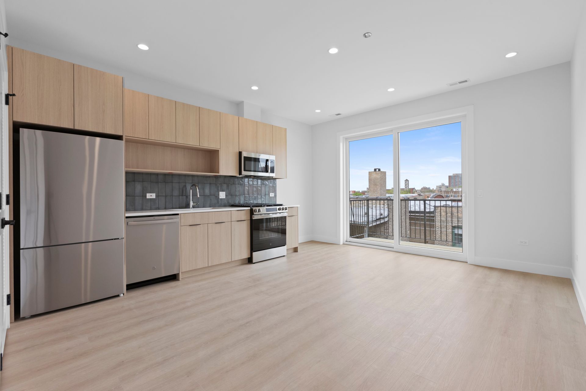 An empty kitchen with stainless steel appliances and wooden cabinets.