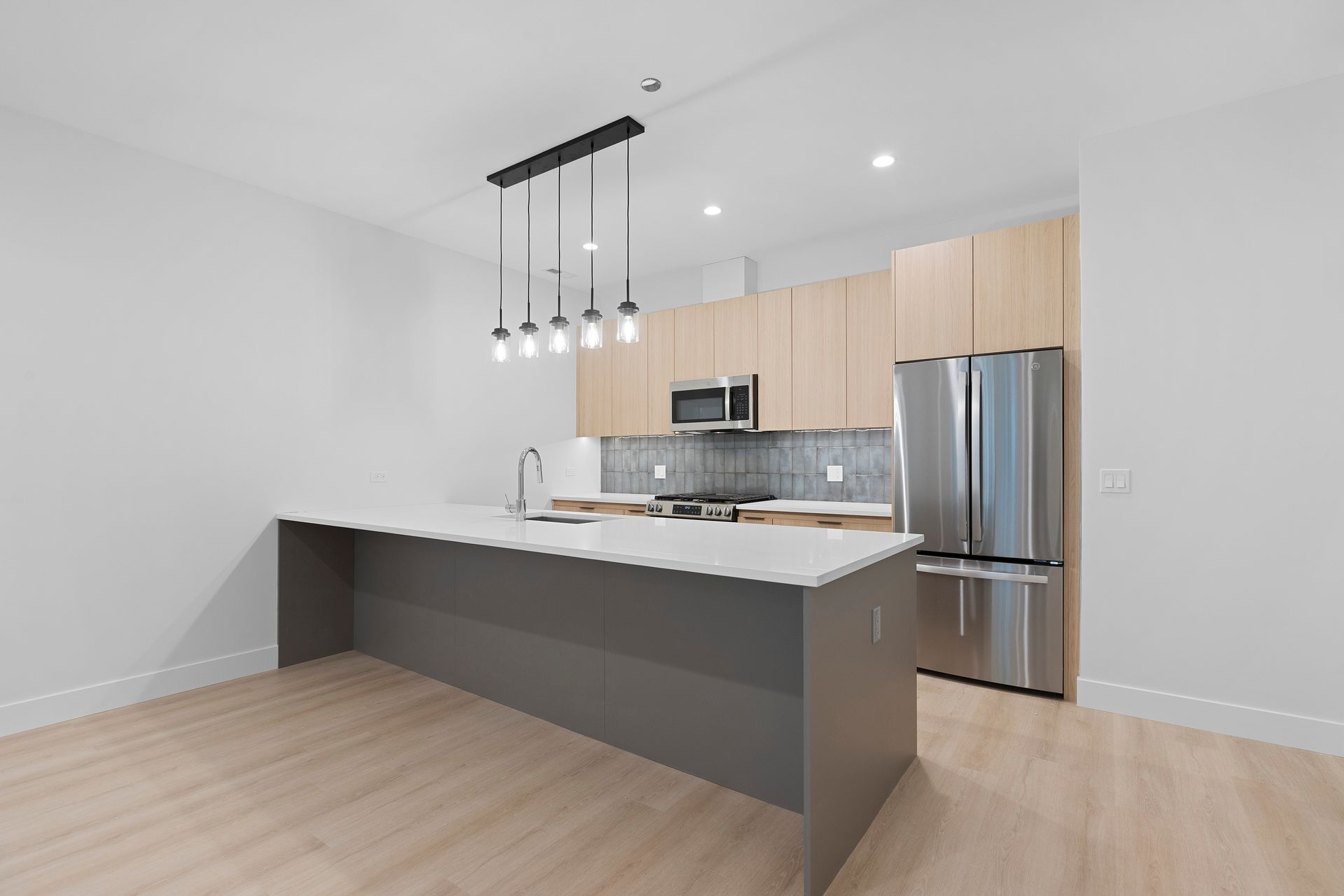 An empty kitchen with a large island and stainless steel appliances