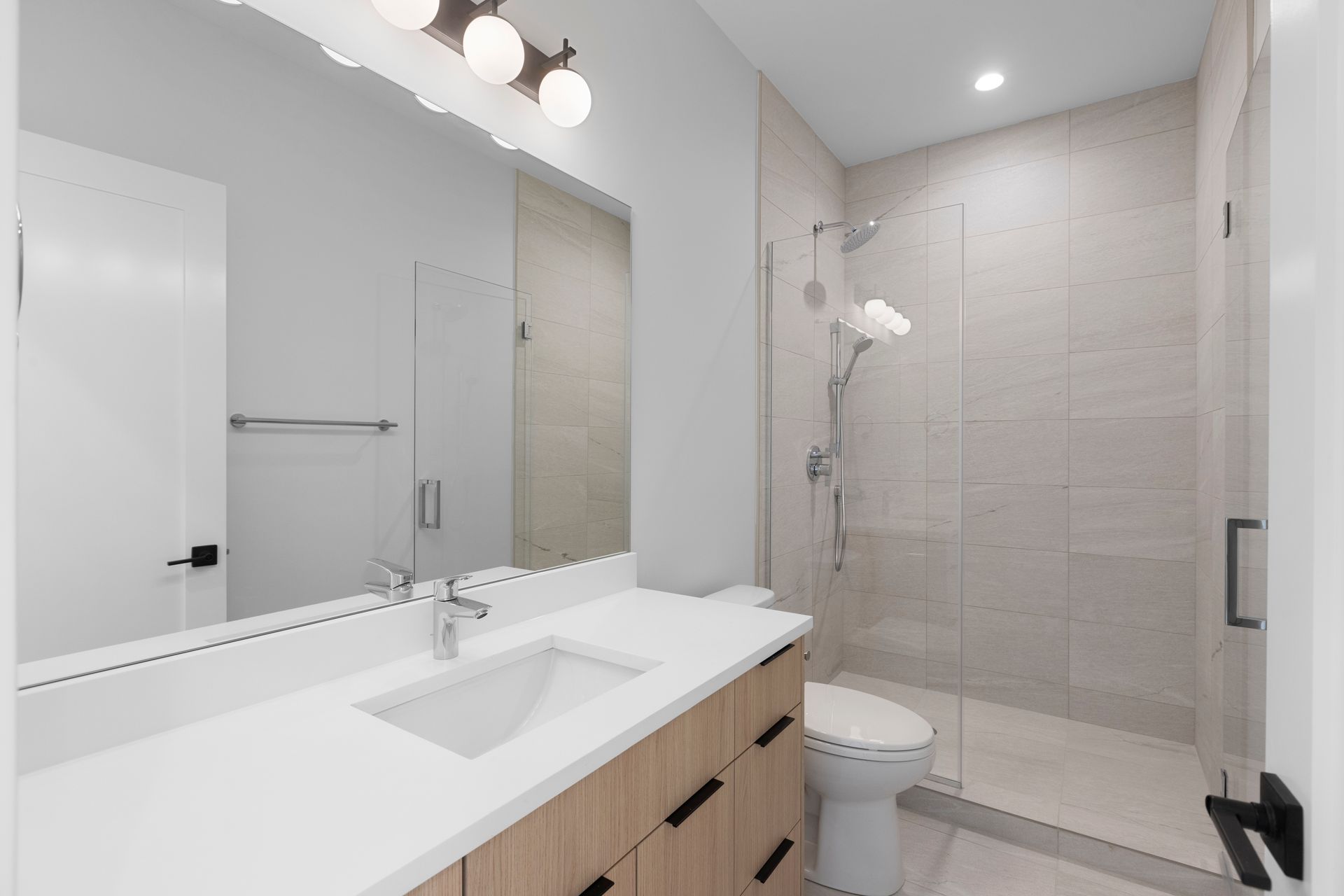 A bathroom with a sink , toilet , shower and mirror.