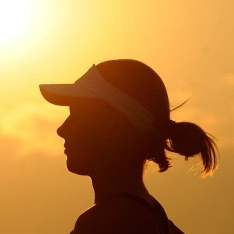 A silhouette of a woman wearing a hat and visor