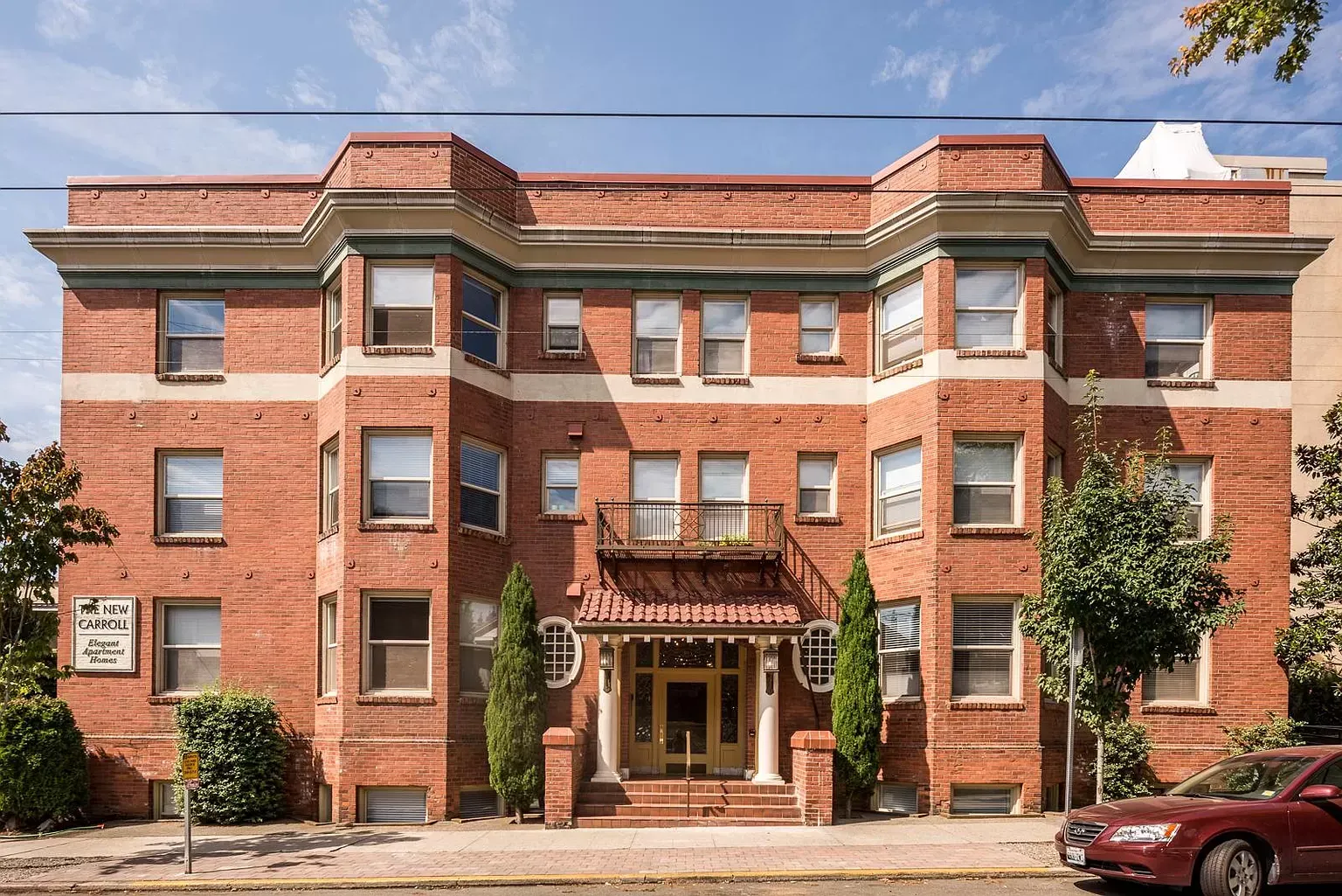 A large brick building with a red car parked in front of it
