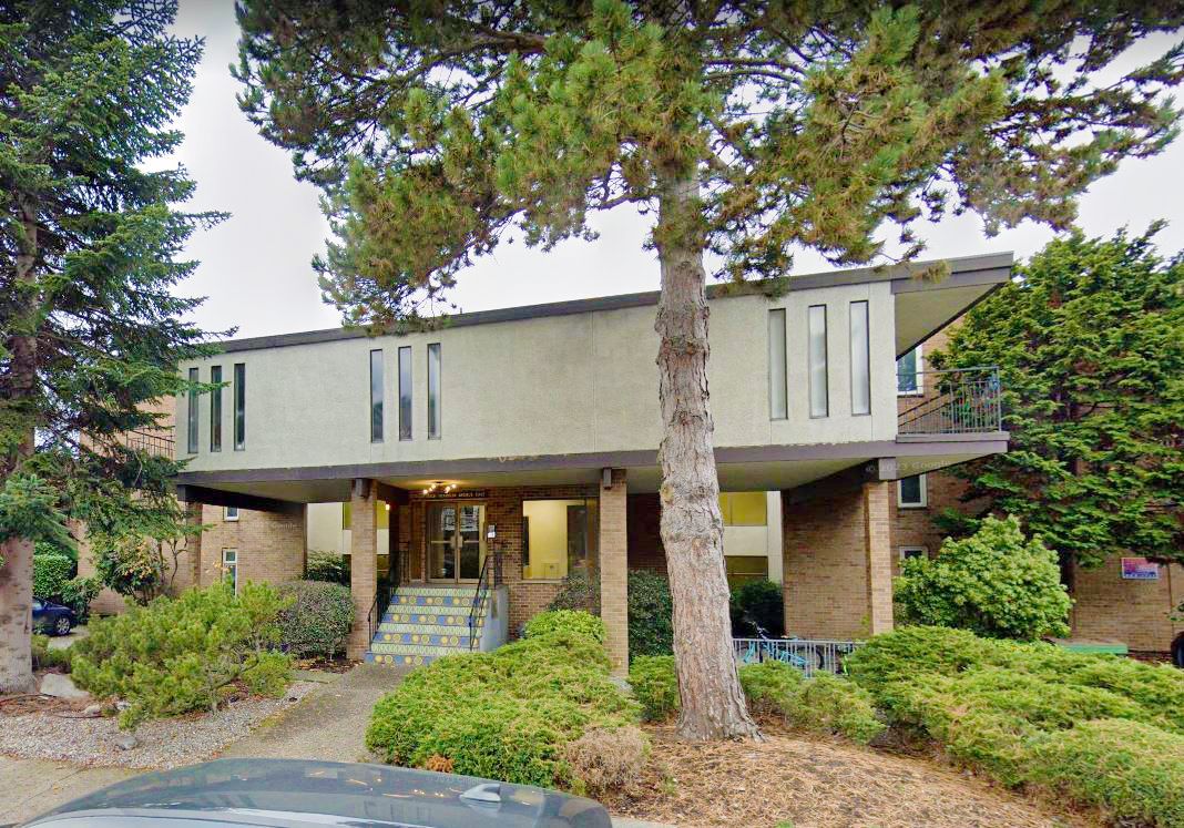 A large brick house with a car parked in front of it surrounded by trees.