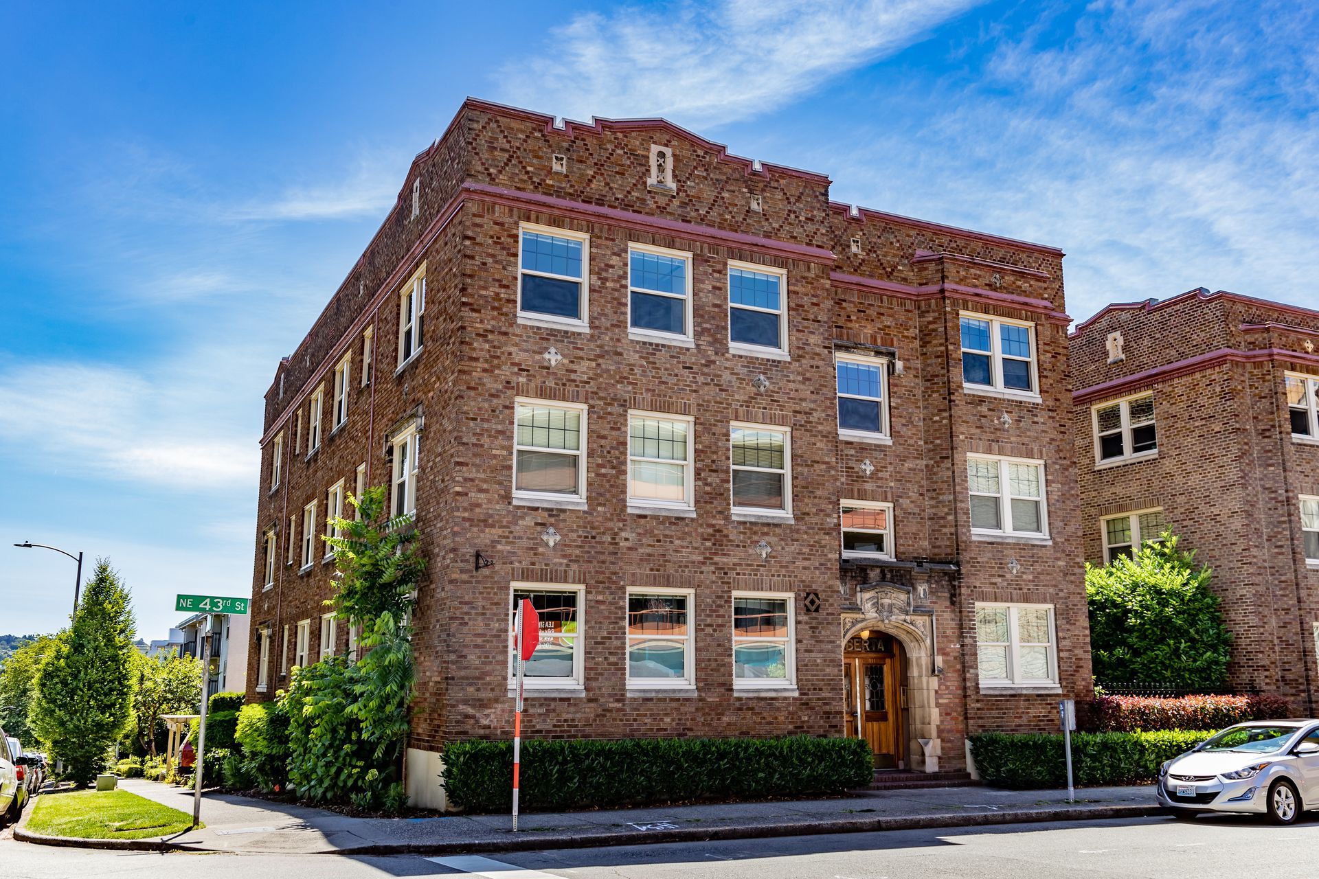A large brick building with a lot of windows is on the corner of a street.