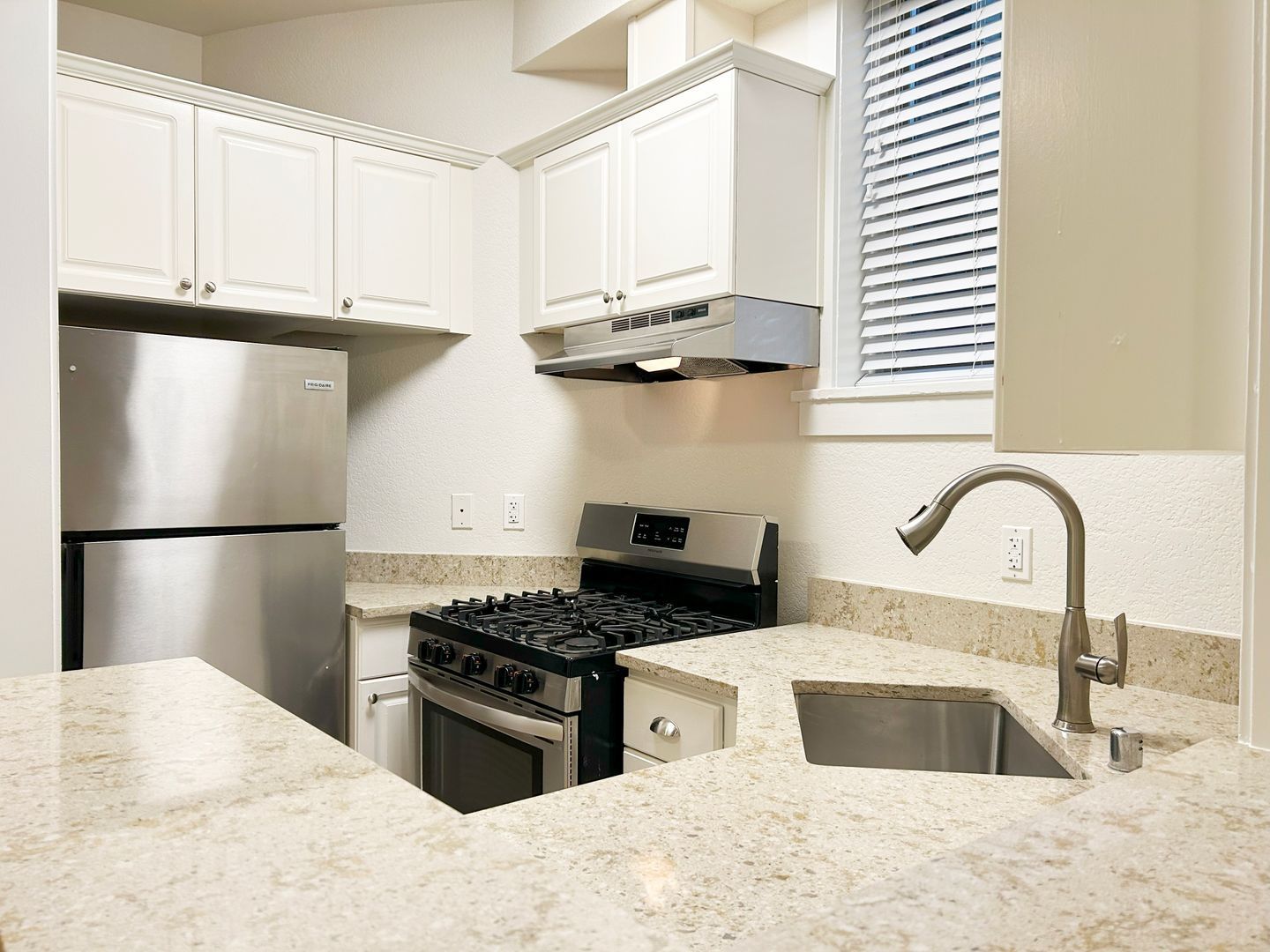 A kitchen with white cabinets stainless steel appliances and a sink