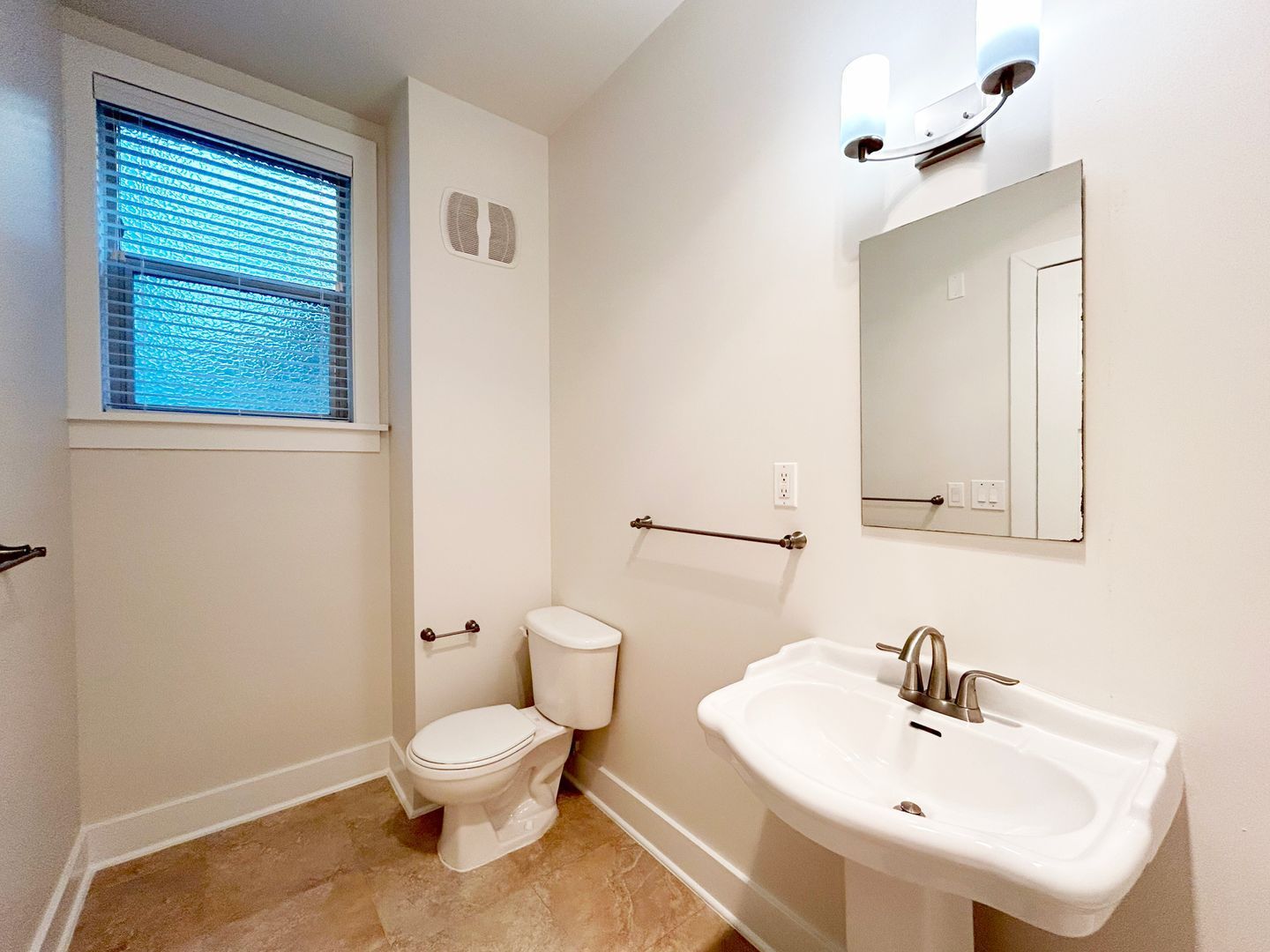 A bathroom with a toilet , sink and mirror