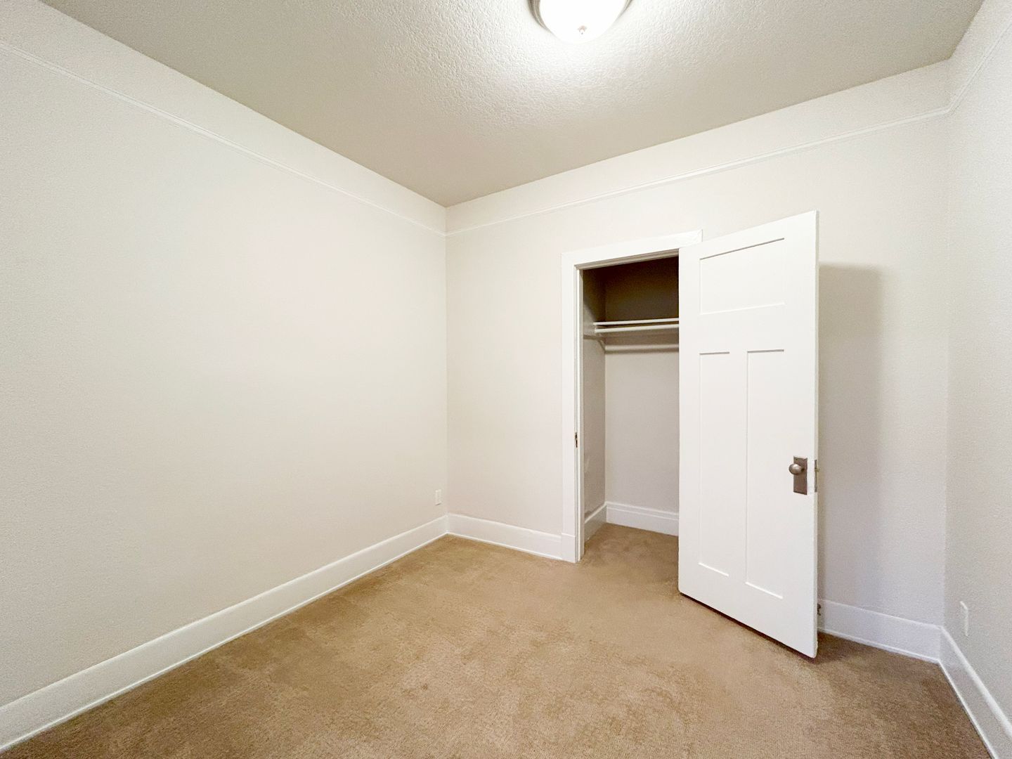 An empty bedroom with a closet and a light on the ceiling.