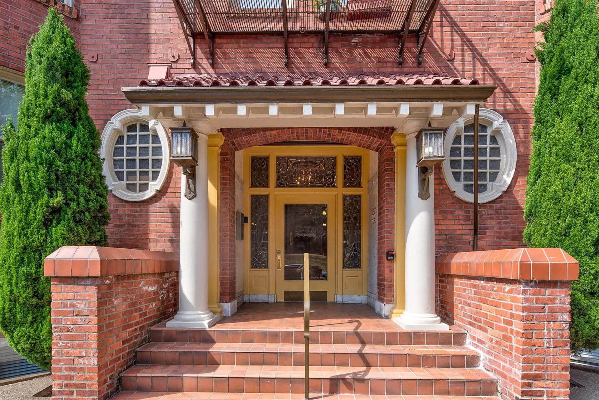 A brick building with a yellow door and stairs